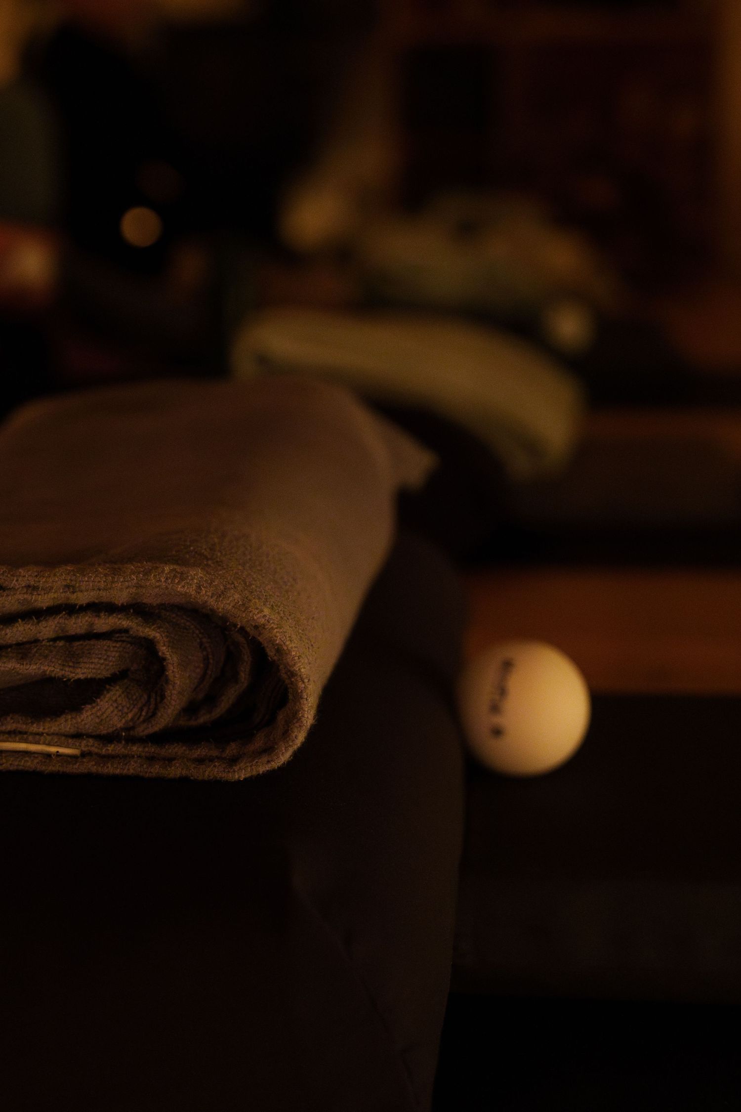 A moody close-up photo of a folded blanket and sphere in dim lighting.