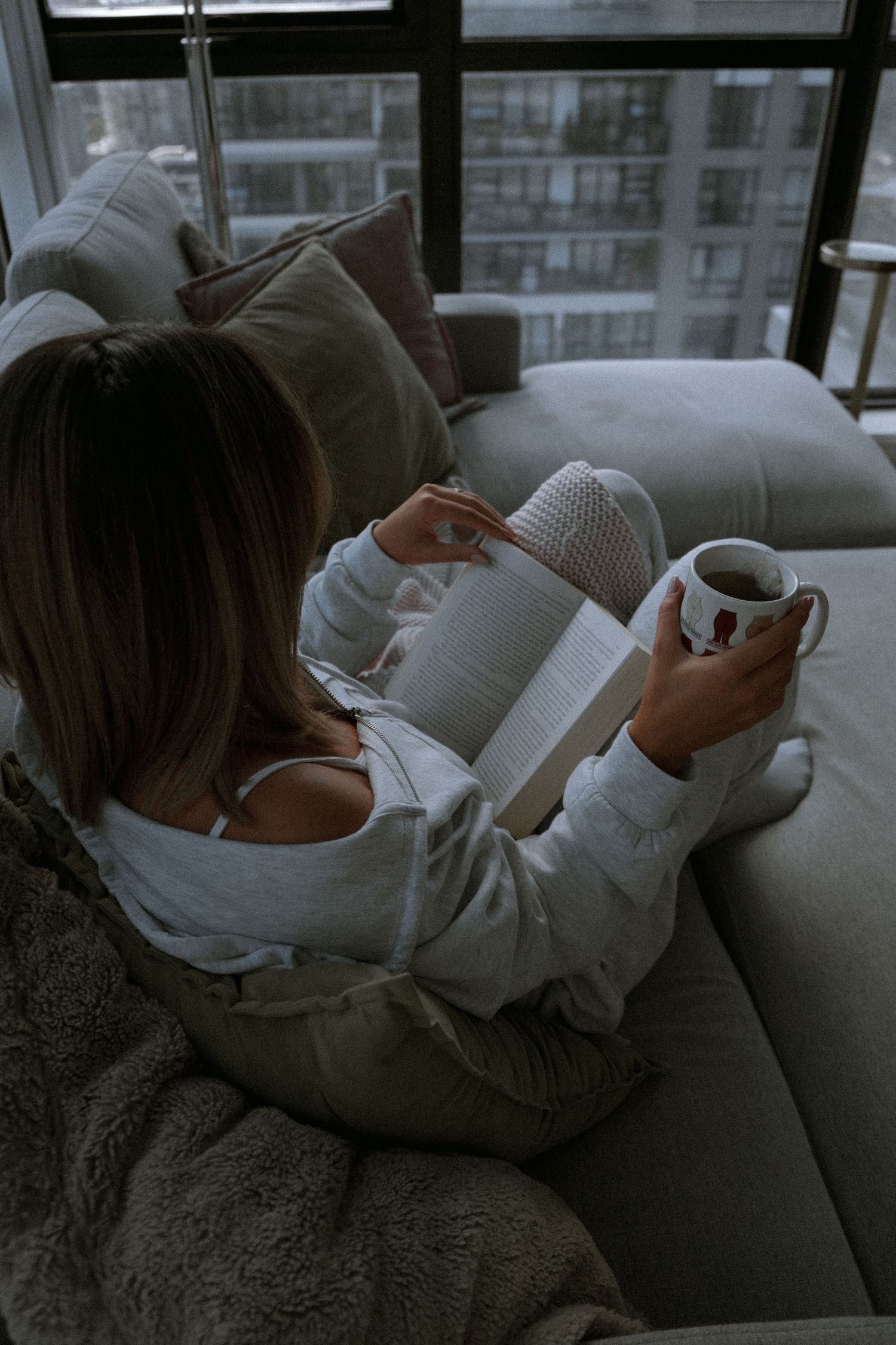 Cozy reading scene with coffee mug and book against city backdrop.