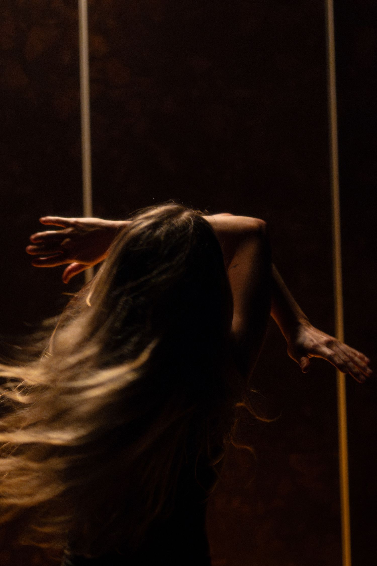 Dancer with flowing hair captured in dynamic motion against dark background.