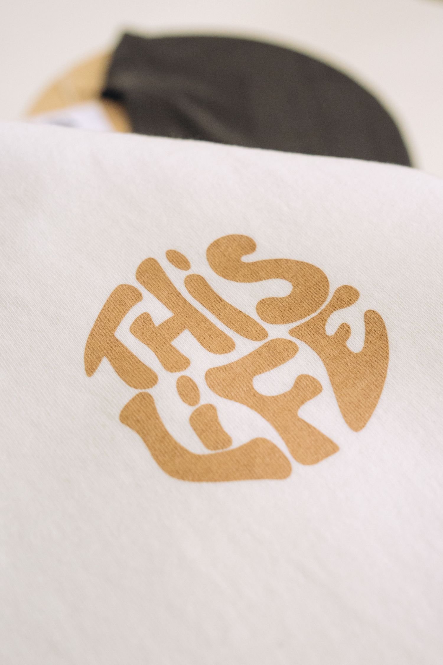 Gold circular logo design on white paper showing text in a stylized arrangement.