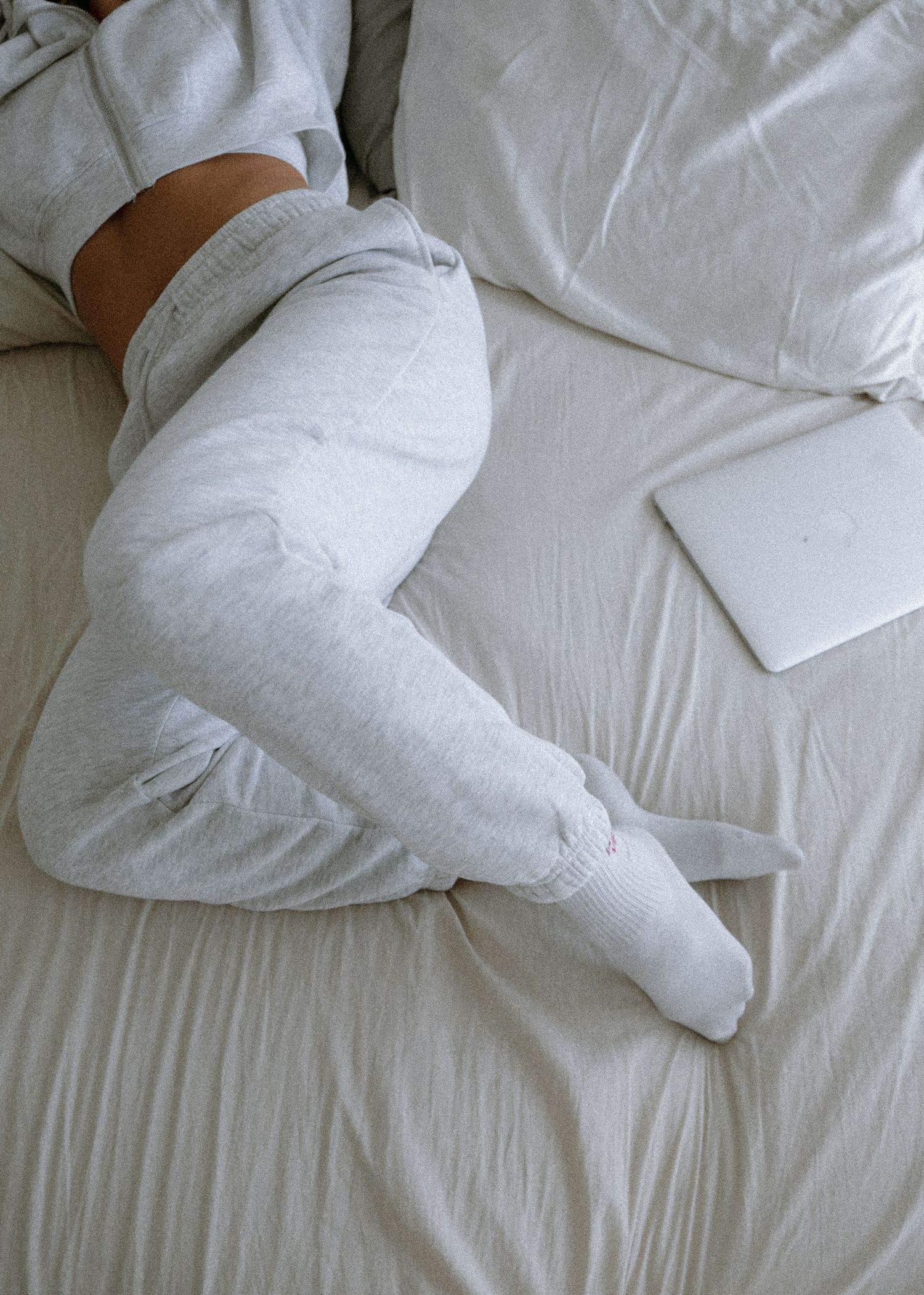 White bedding and pillows on a cozy bed with a MacBook.