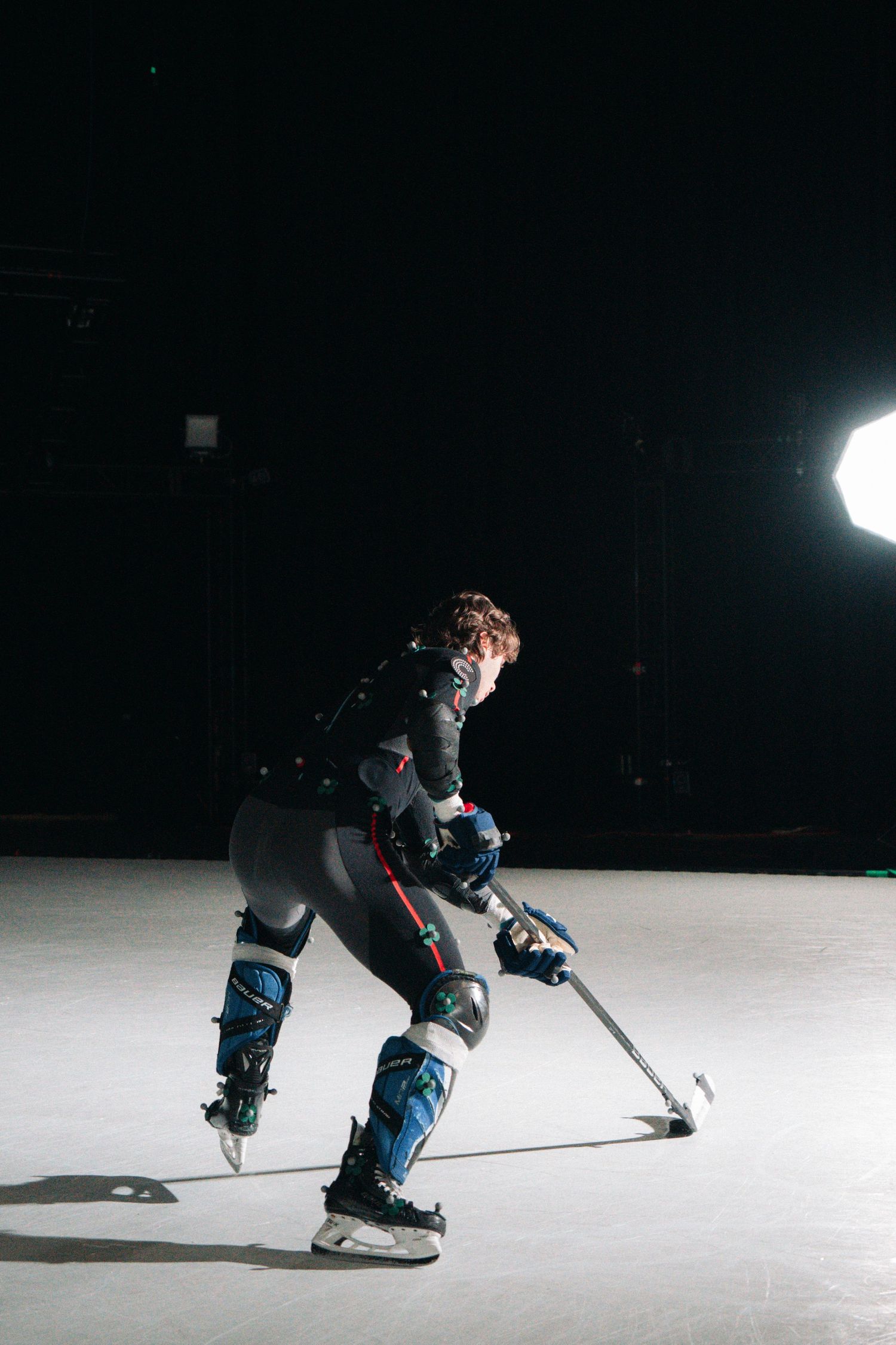 Performer in motion capture gear practices movement sequences in a darkened studio.