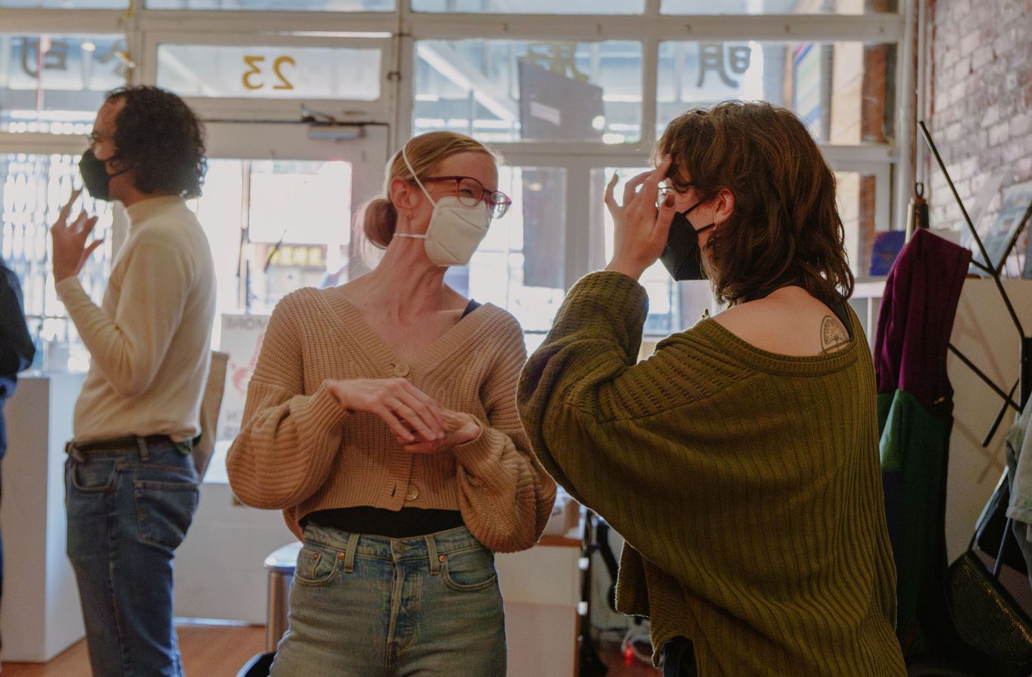 People wearing masks having conversations in bright indoor space.