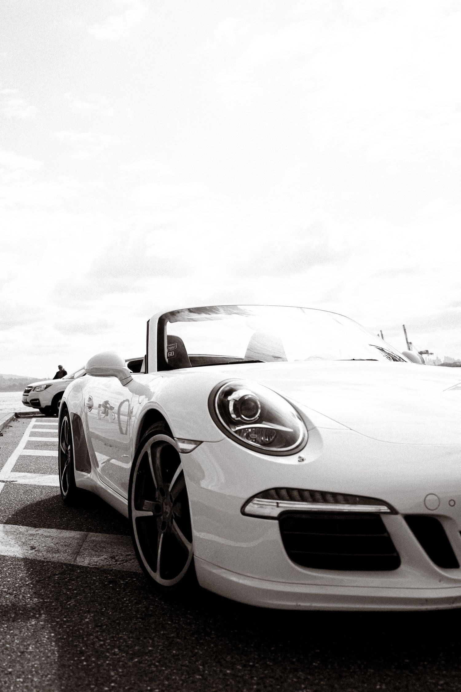 Front view of a white Porsche 911 sports car with sleek headlights and black wheels.