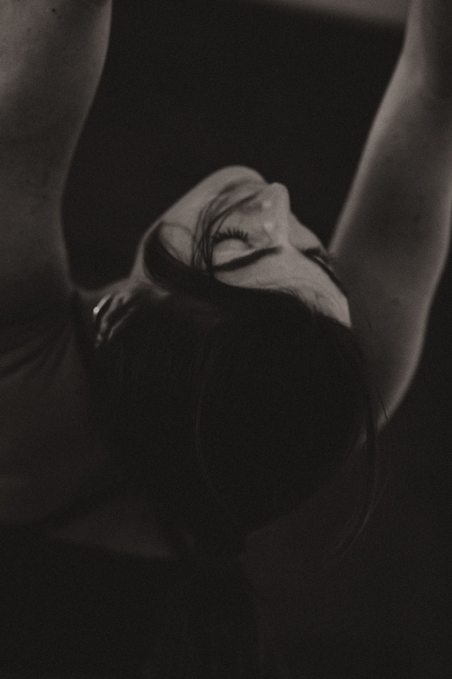 Atmospheric black and white portrait showing peaceful expression in dramatic lighting.