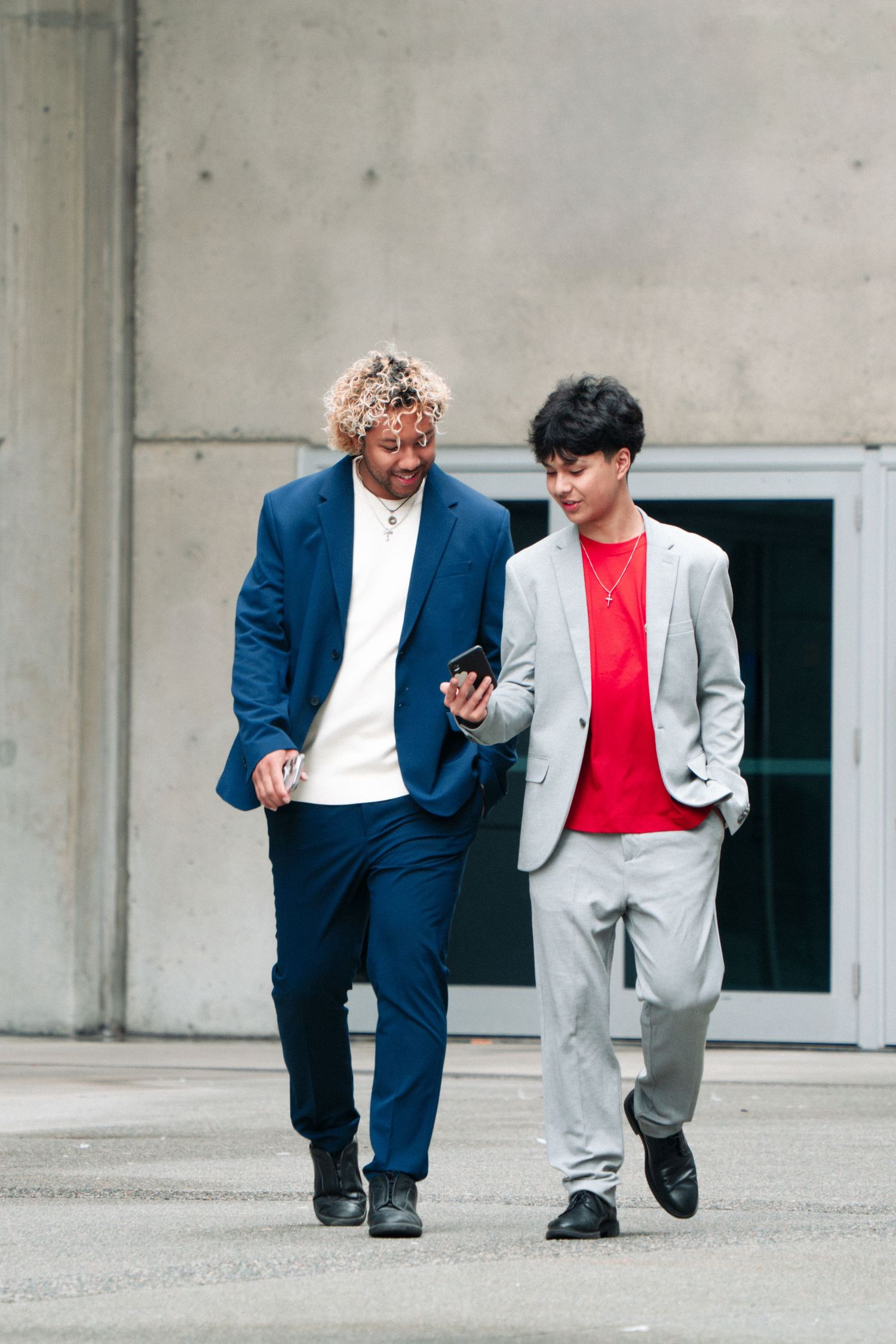 Two fashion models walking together wearing coordinated formal attire.