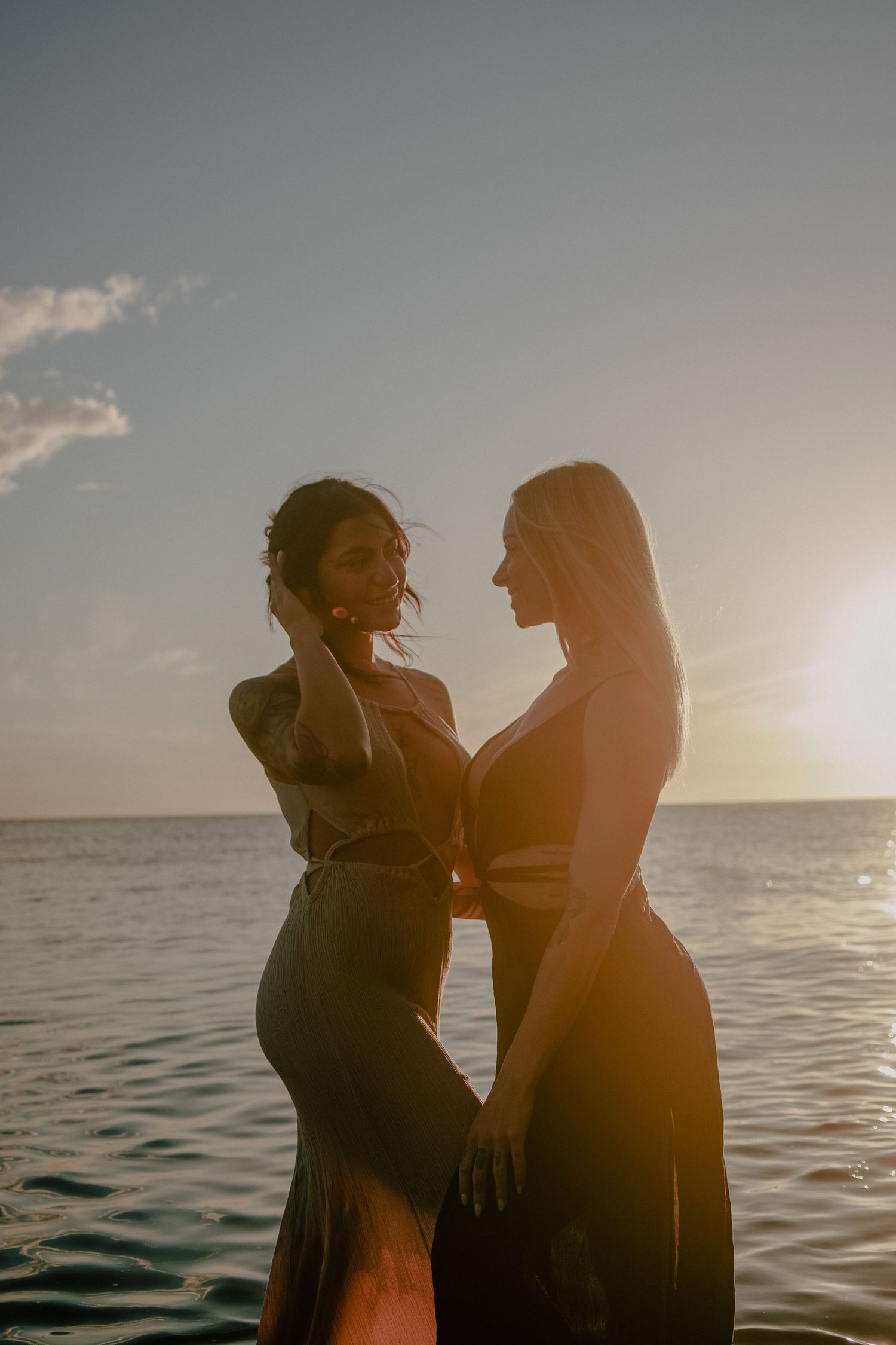 Romantic silhouette of two people embracing against a golden sunset over the ocean.