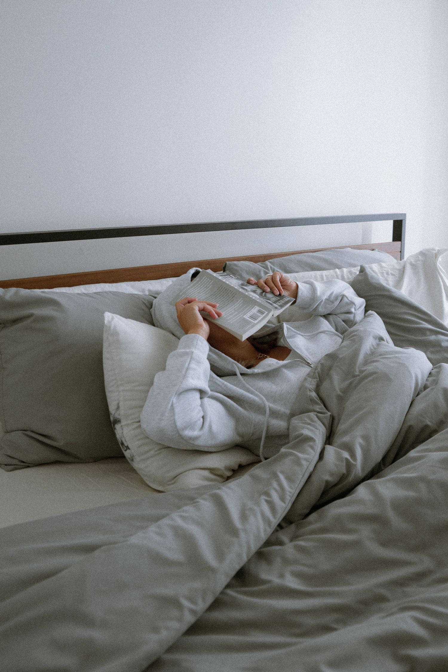 Relaxing reading moment in bed with white comfortable bedding.