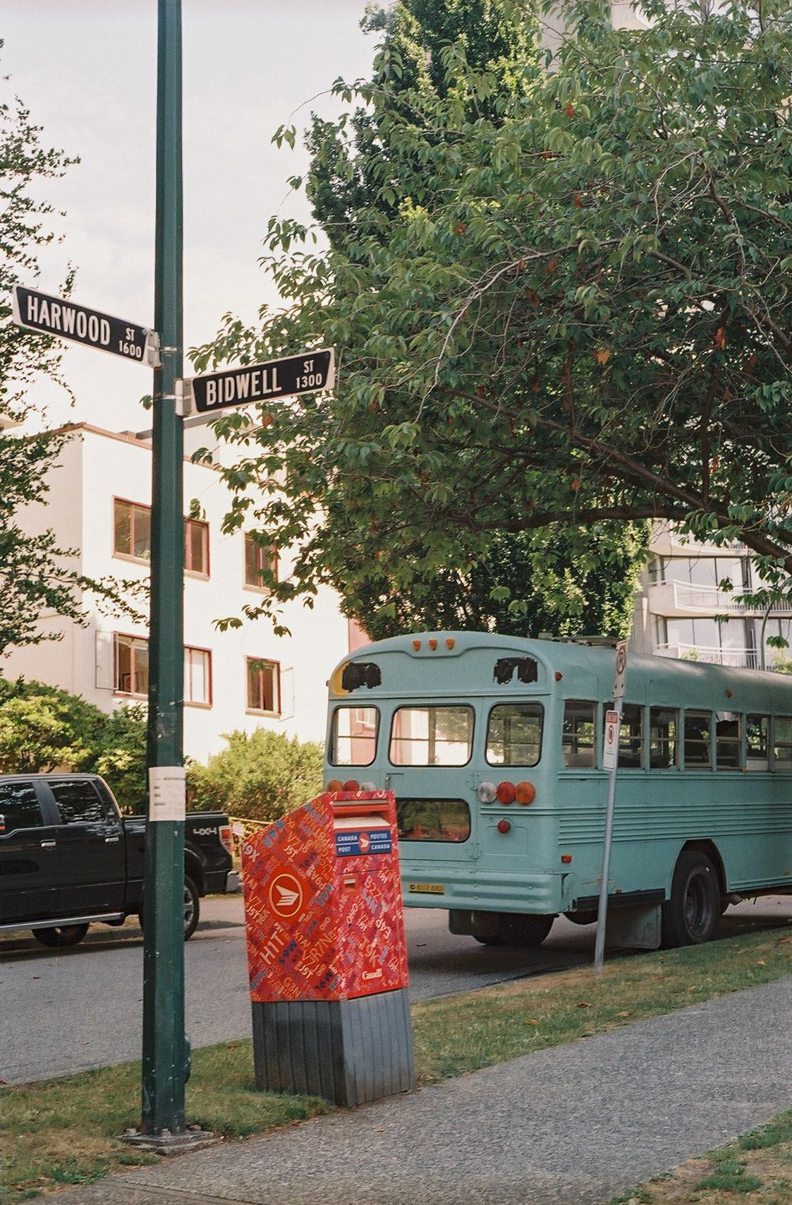 Vintage blue bus parked at intersection of Woodland and Bidwell streets.
