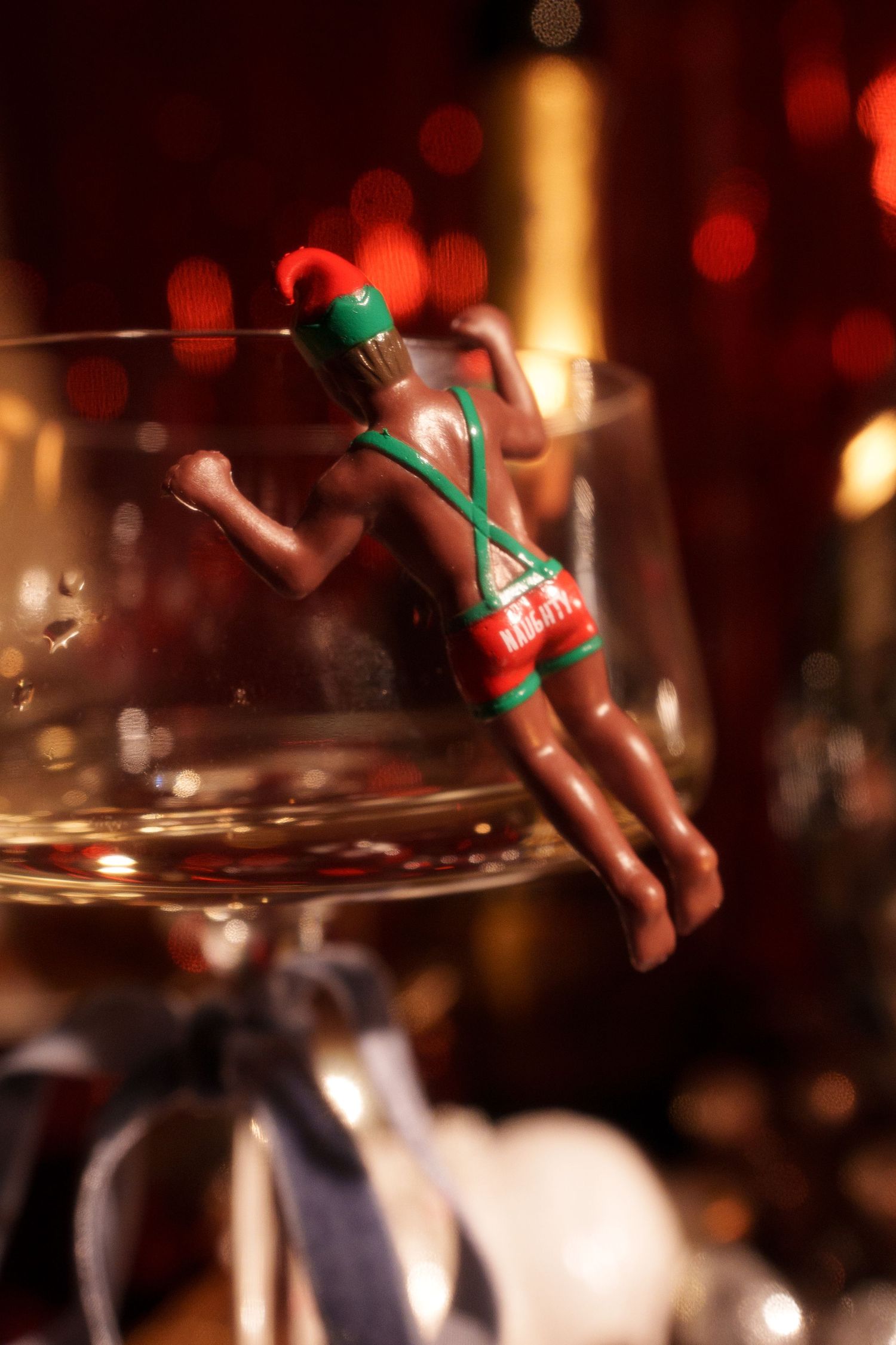 Small decorative diver figure balanced on edge of champagne glass with bokeh background.