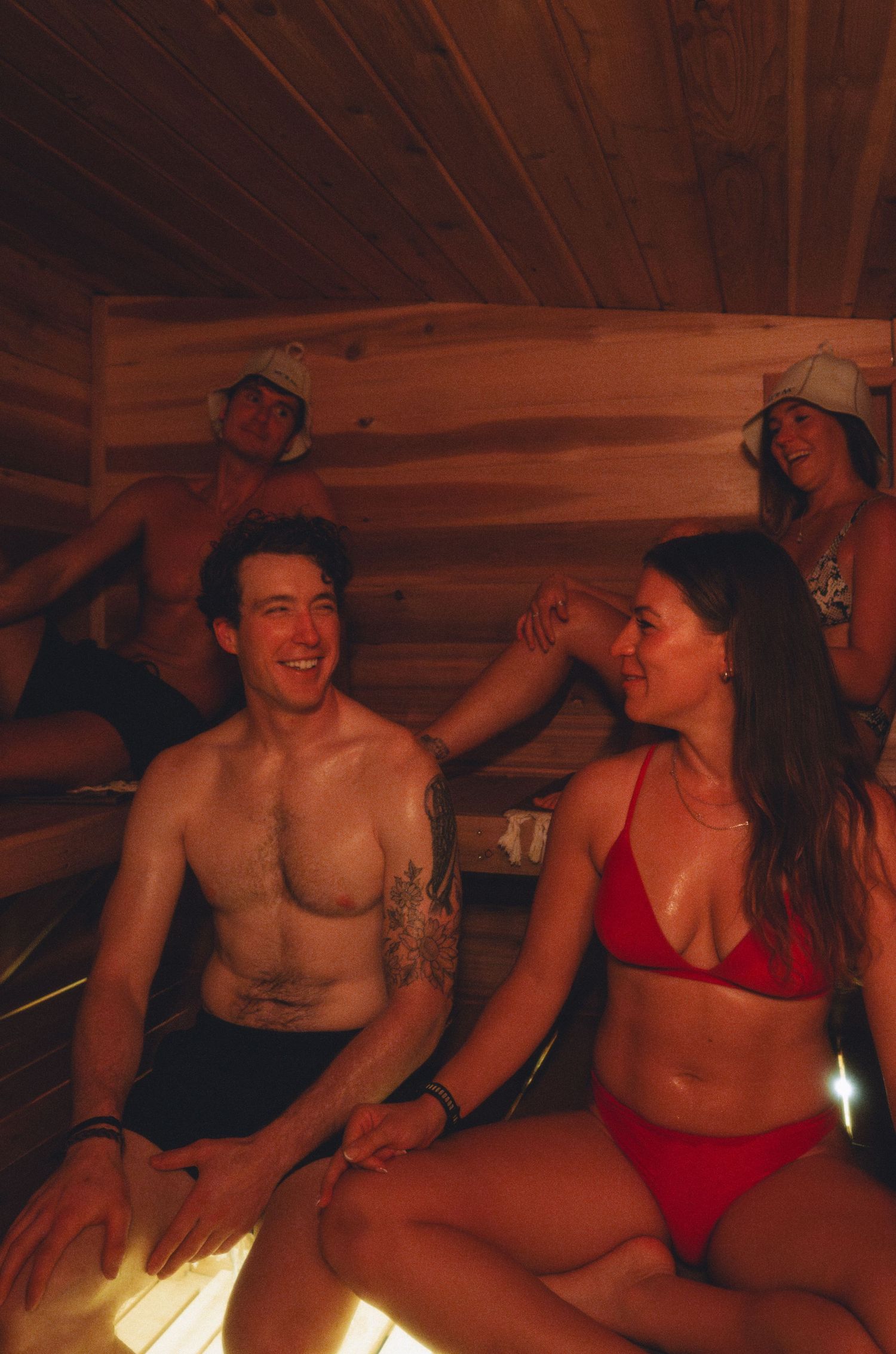 Group enjoying themselves inside wooden sauna or cabin.