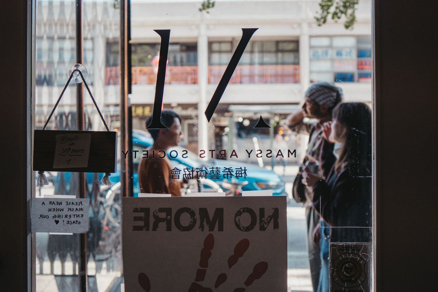View through glass door showing reversed text and people in conversation.