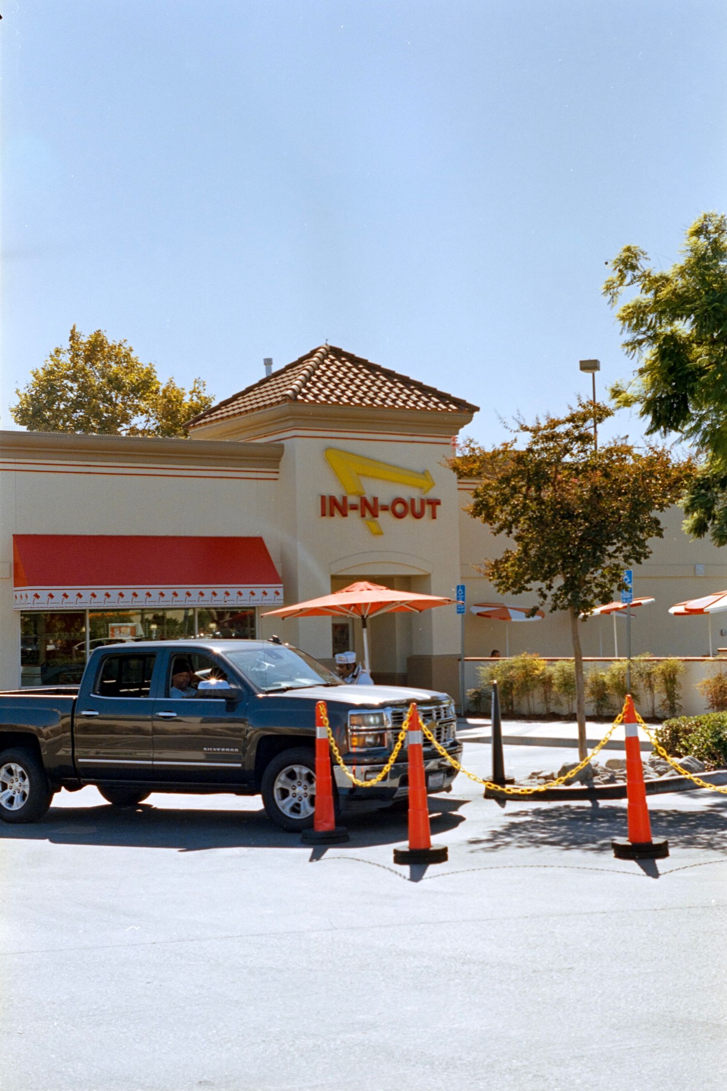 In-N-Out Burger restaurant exterior with Spanish tile roof and black pickup truck in parking lot.
