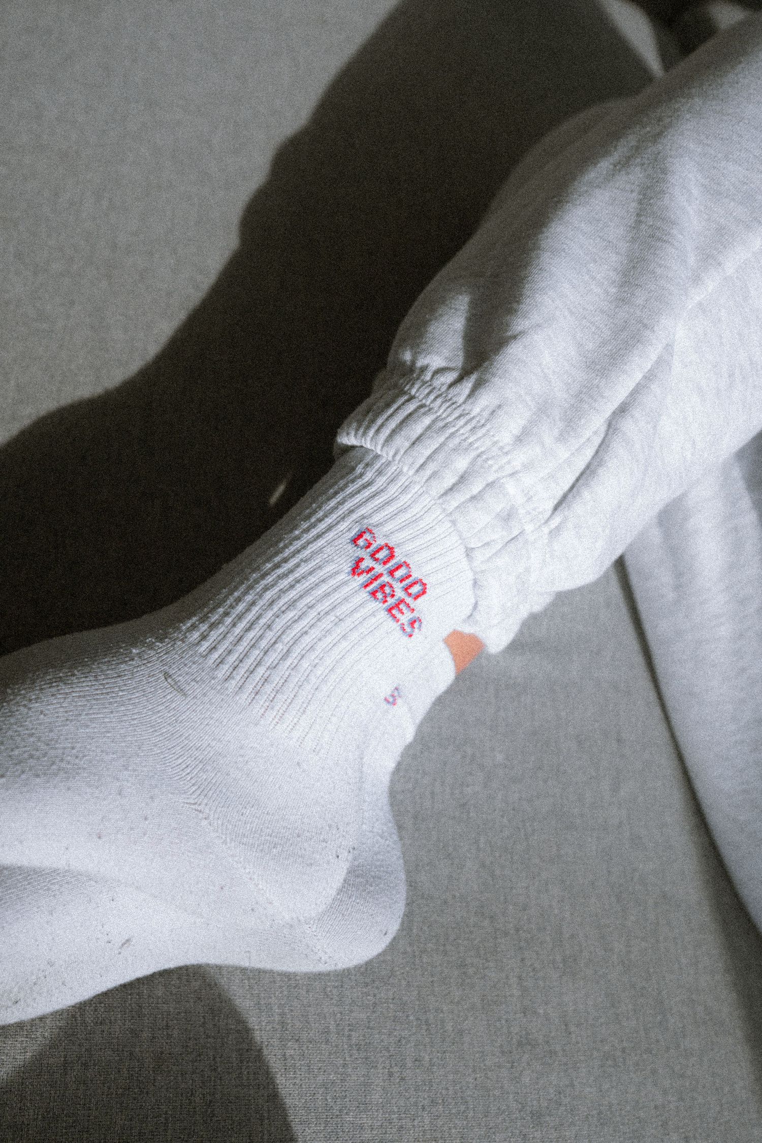 Close-up of white socks with red text against gray background.