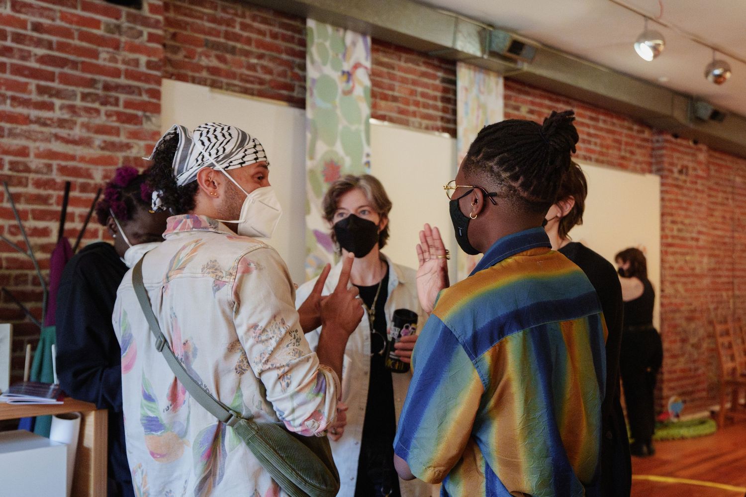 Group of masked attendees having an animated conversation at an indoor gathering.