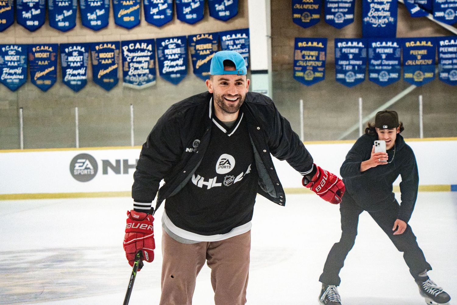 Two hockey players skating on an ice rink with championship banners displayed above.