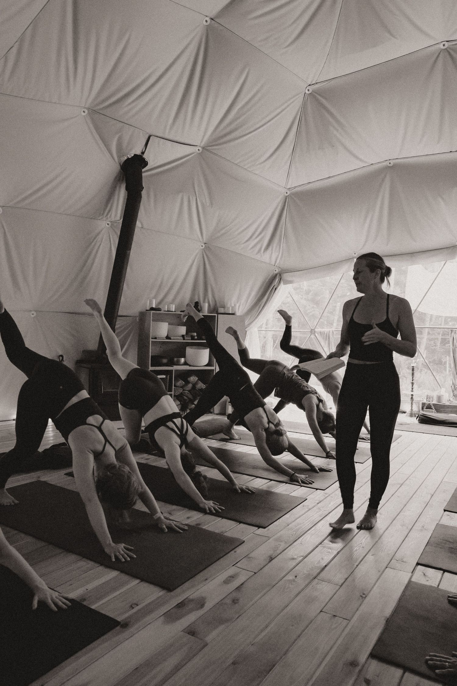 A black and white photo of a yoga class in session inside a geometric dome structure.