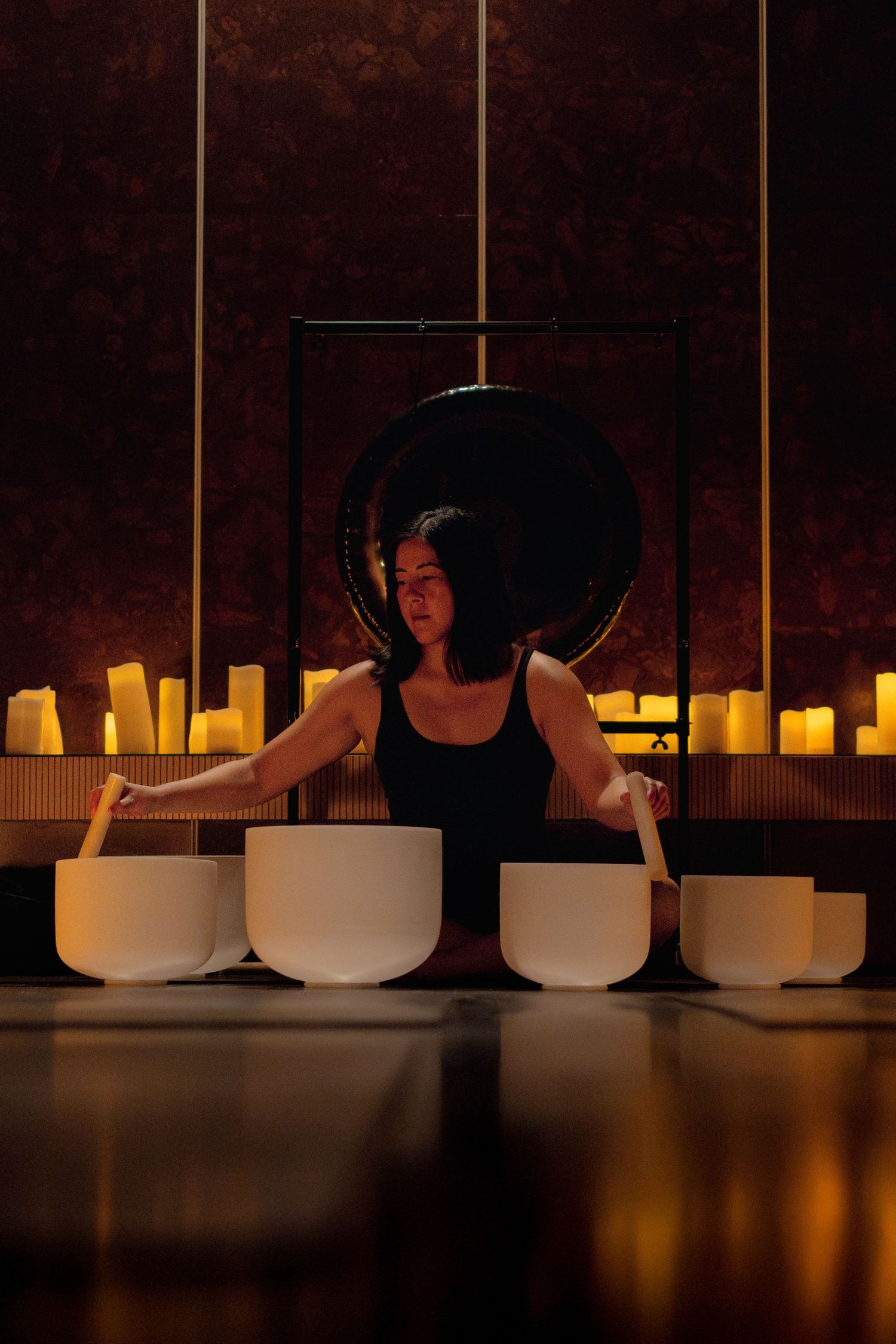 Sound healing setup with crystal bowls and candles in mystical dark environment.