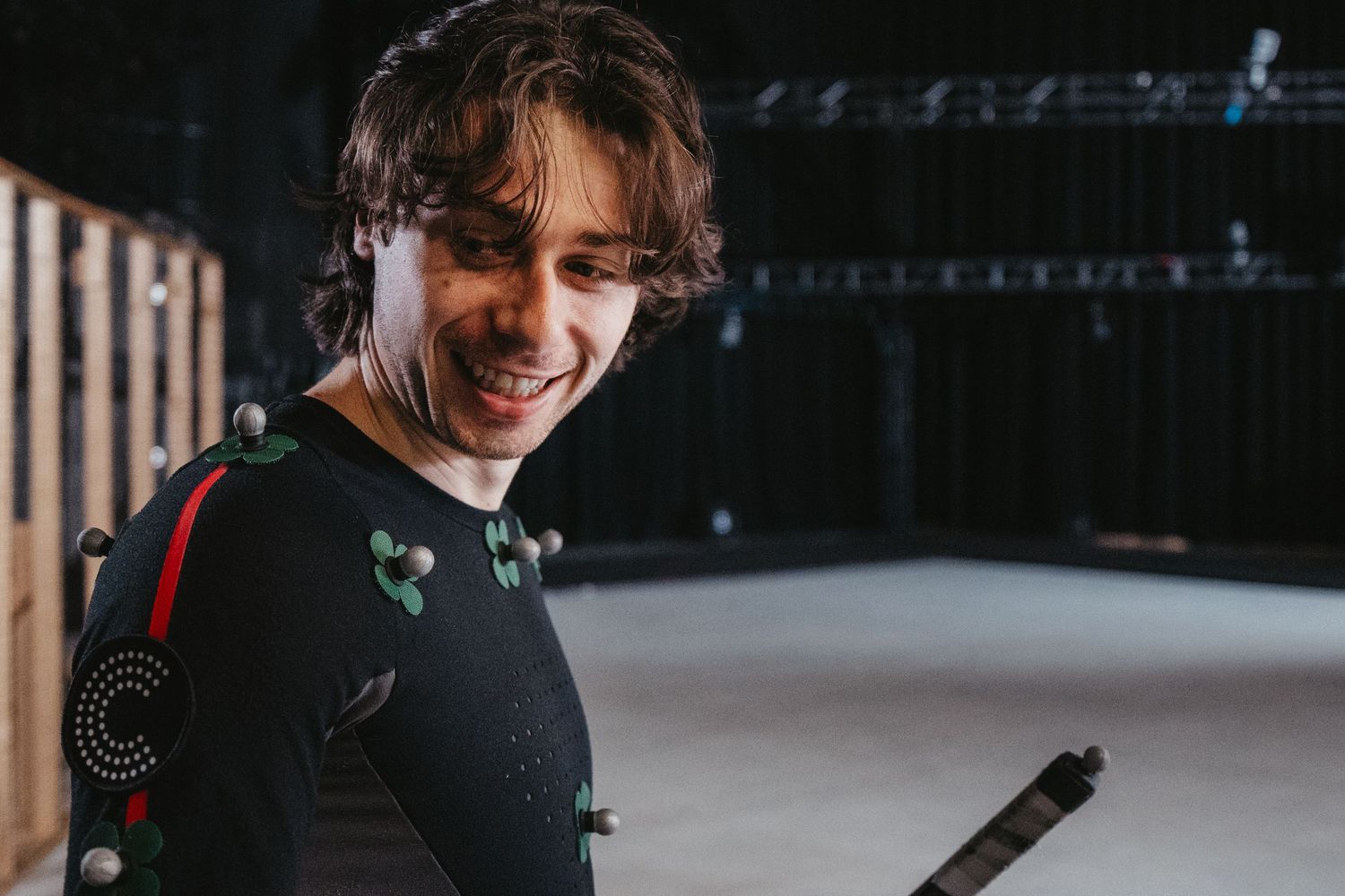 Motion capture performer in black suit with tracking markers during a studio session.