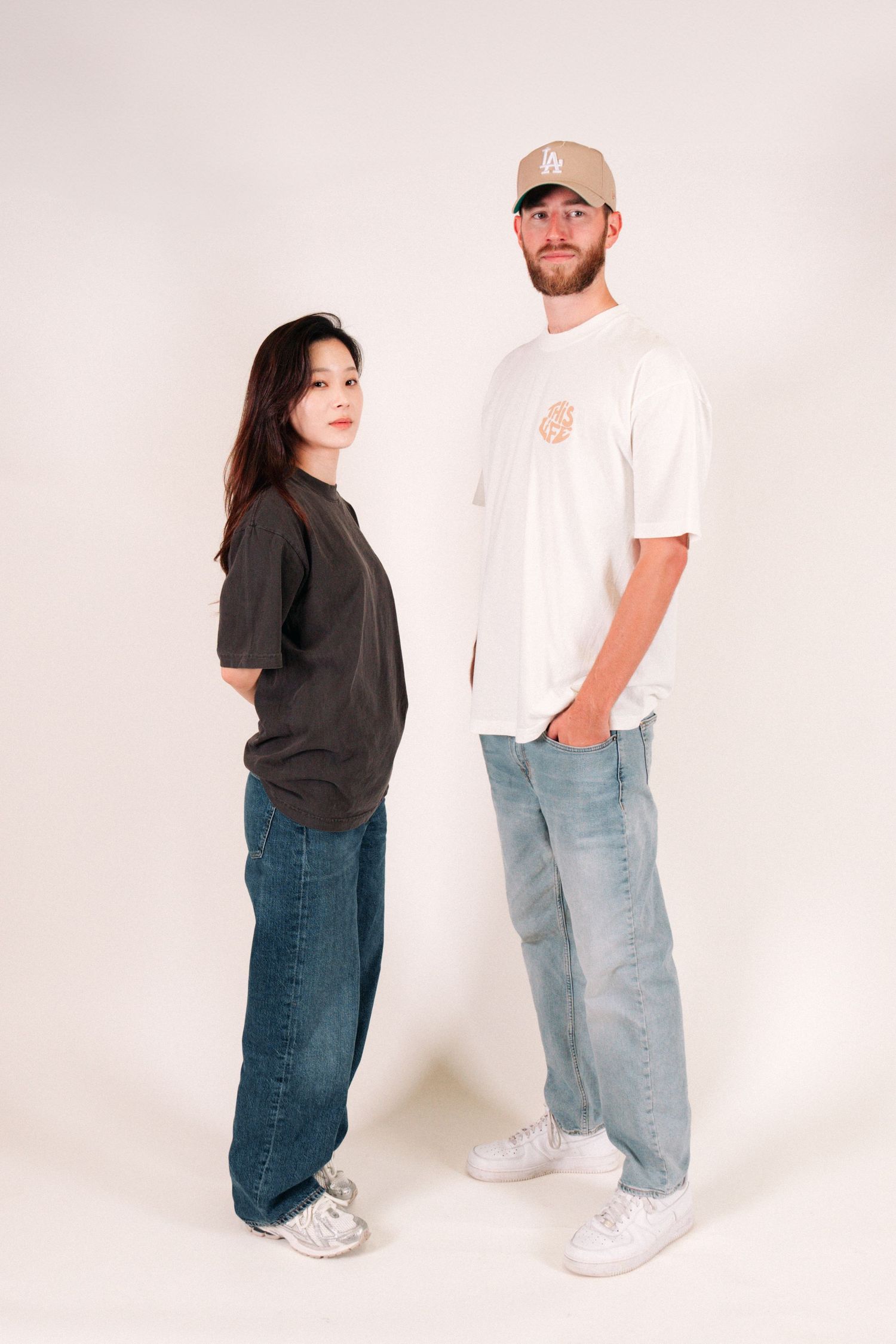 Two people modeling casual streetwear against white studio background.