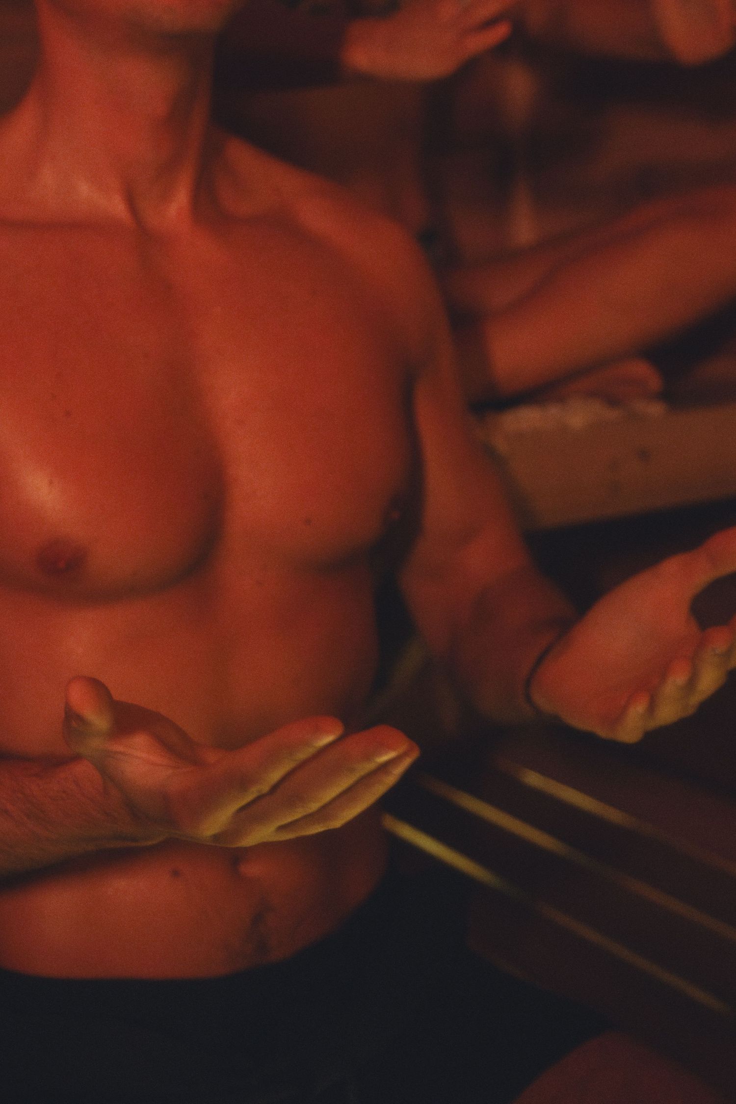 Moody red-tinted photo of torso under dim lighting.