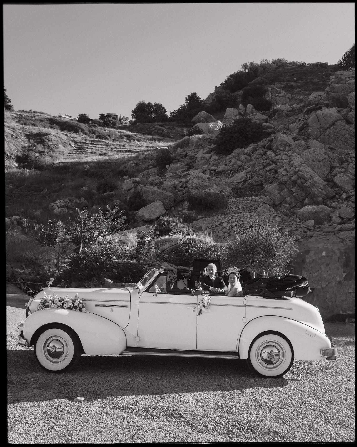A black and white photo of four vintage luxury convertible cars parked in a scenic desert landscape.