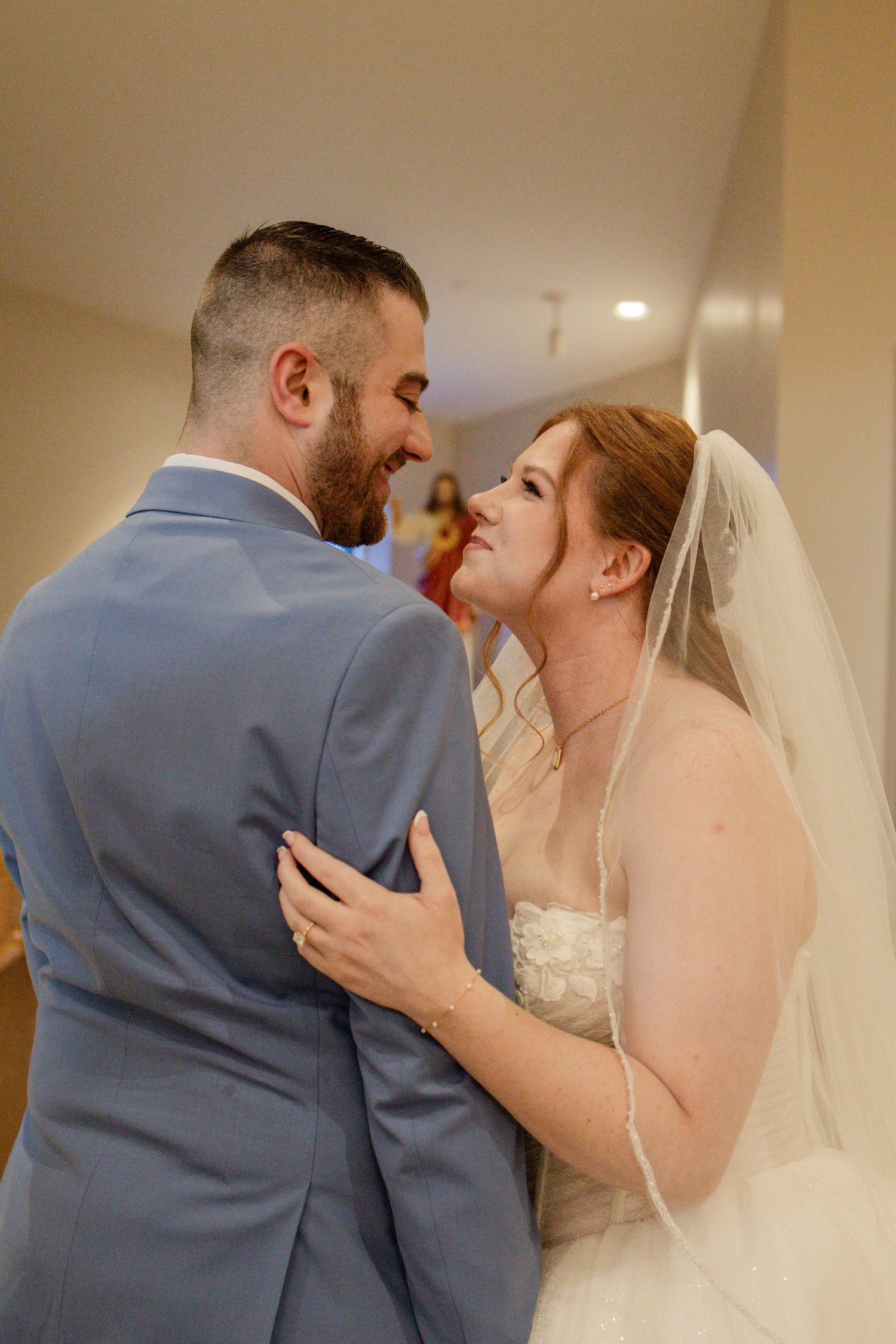 A tender moment between newlyweds as they share an intimate embrace, with the bride in white and groom in gray.