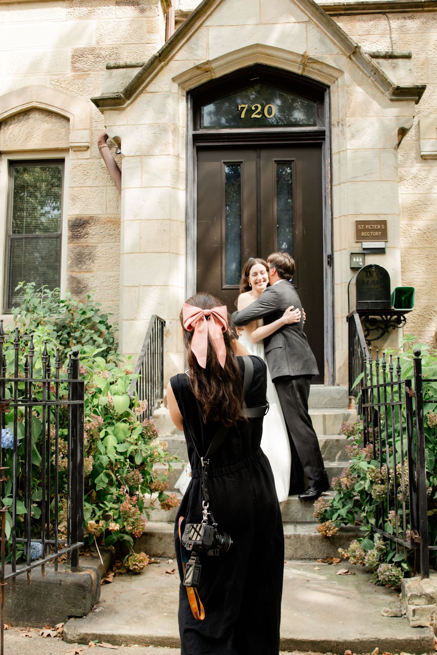 A sequence of five photos showing a couple embracing in front of a historic brownstone building entrance with plants.