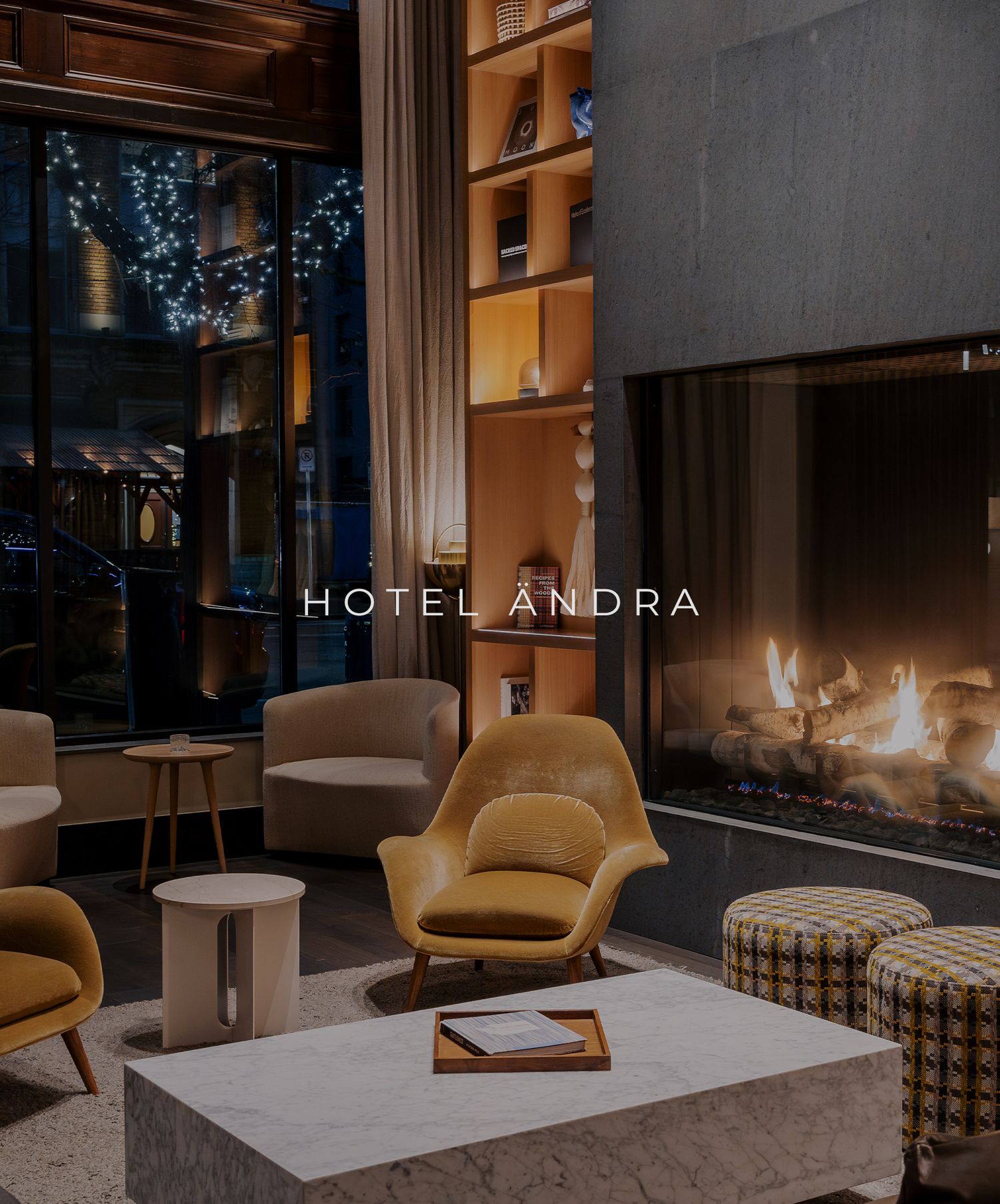 Modern hotel lobby lounge featuring tan armchairs, a linear fireplace, and soft blue lighting at Hotel Andra.