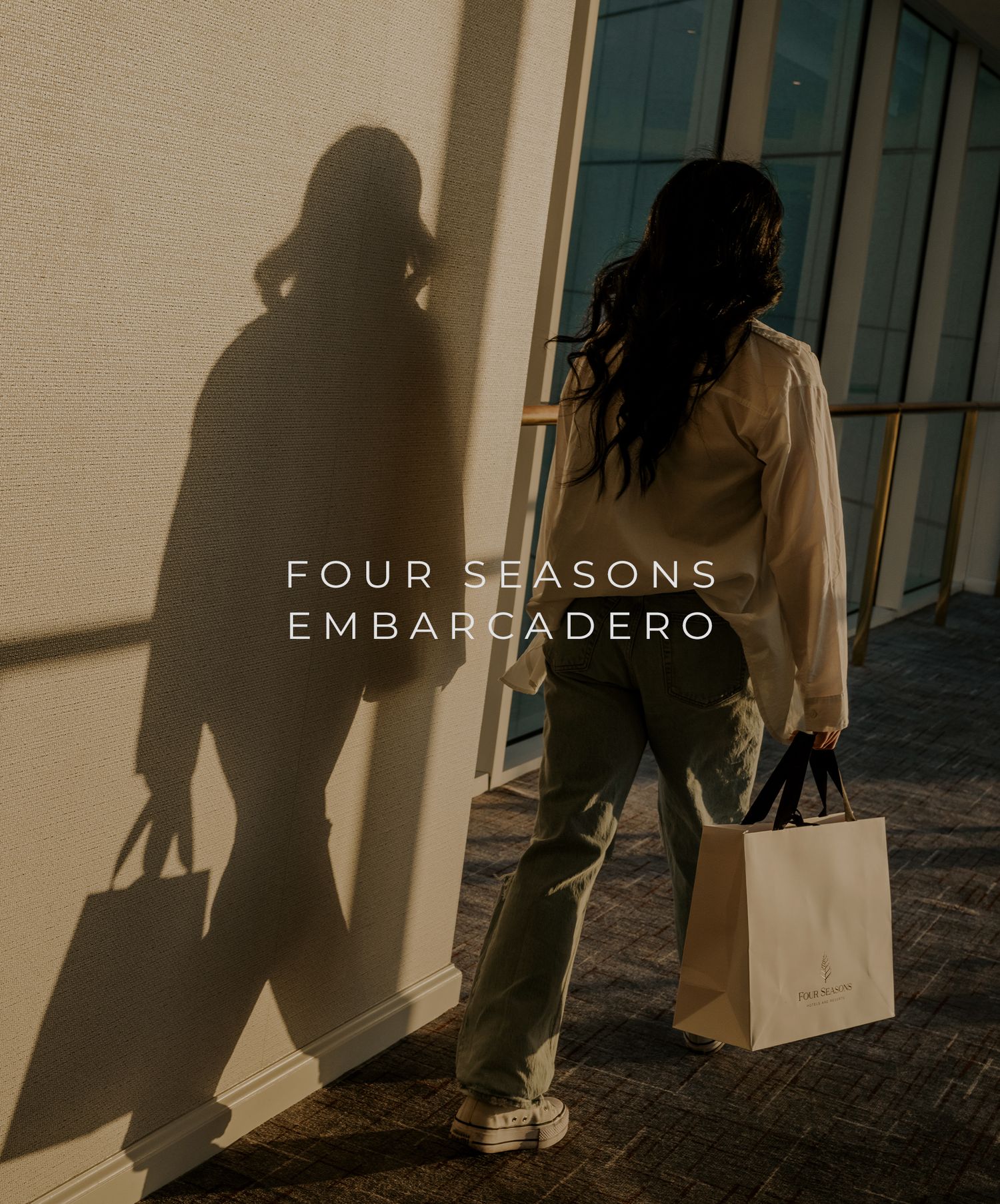 Figure in beige outfit casts dramatic shadow on wall while shopping at Four Seasons Embarcadero.