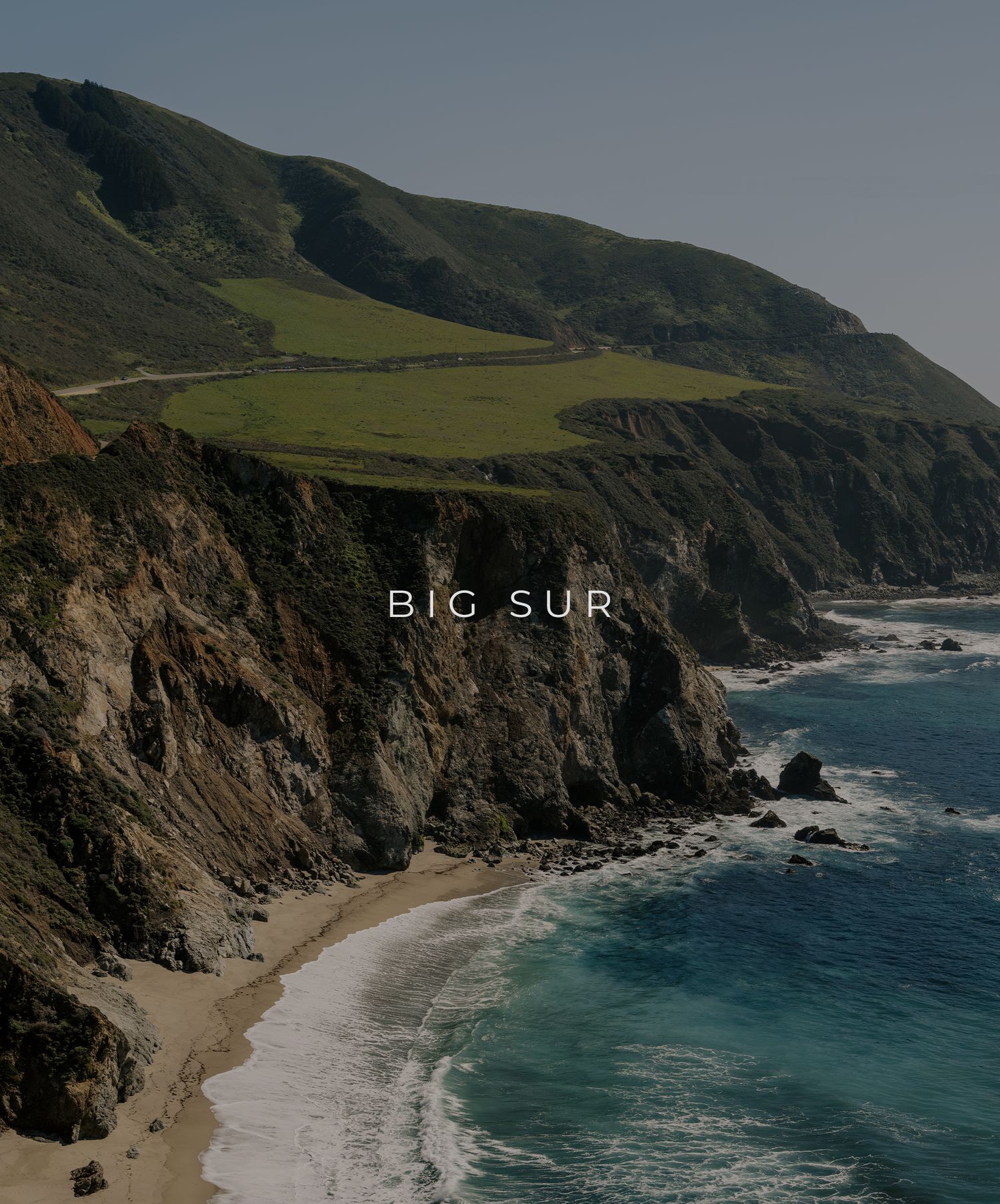 Dramatic coastal cliffs and turquoise waters along Big Sur's rugged California coastline with green hills above.