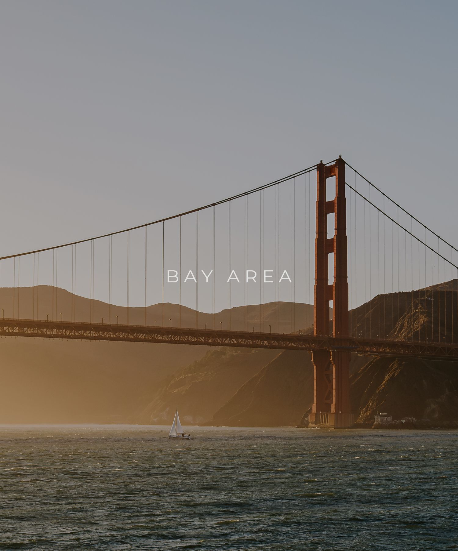 Golden Gate Bridge silhouetted against hazy sunset sky in San Francisco Bay Area.