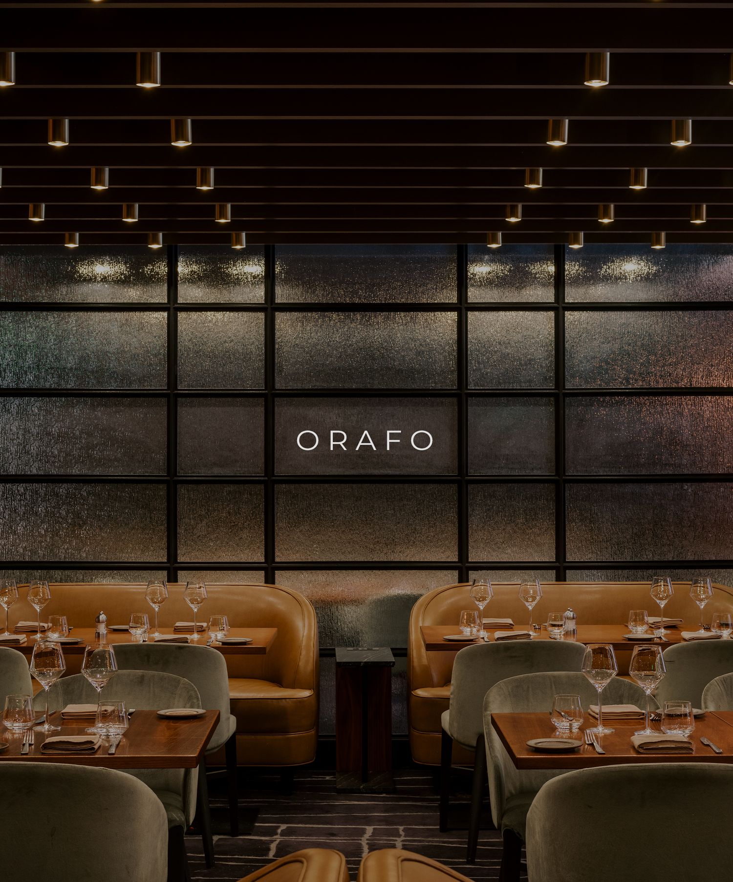 Modern restaurant interior of ORAFO featuring dark wood ceiling beams, ambient lighting and elegant table settings.