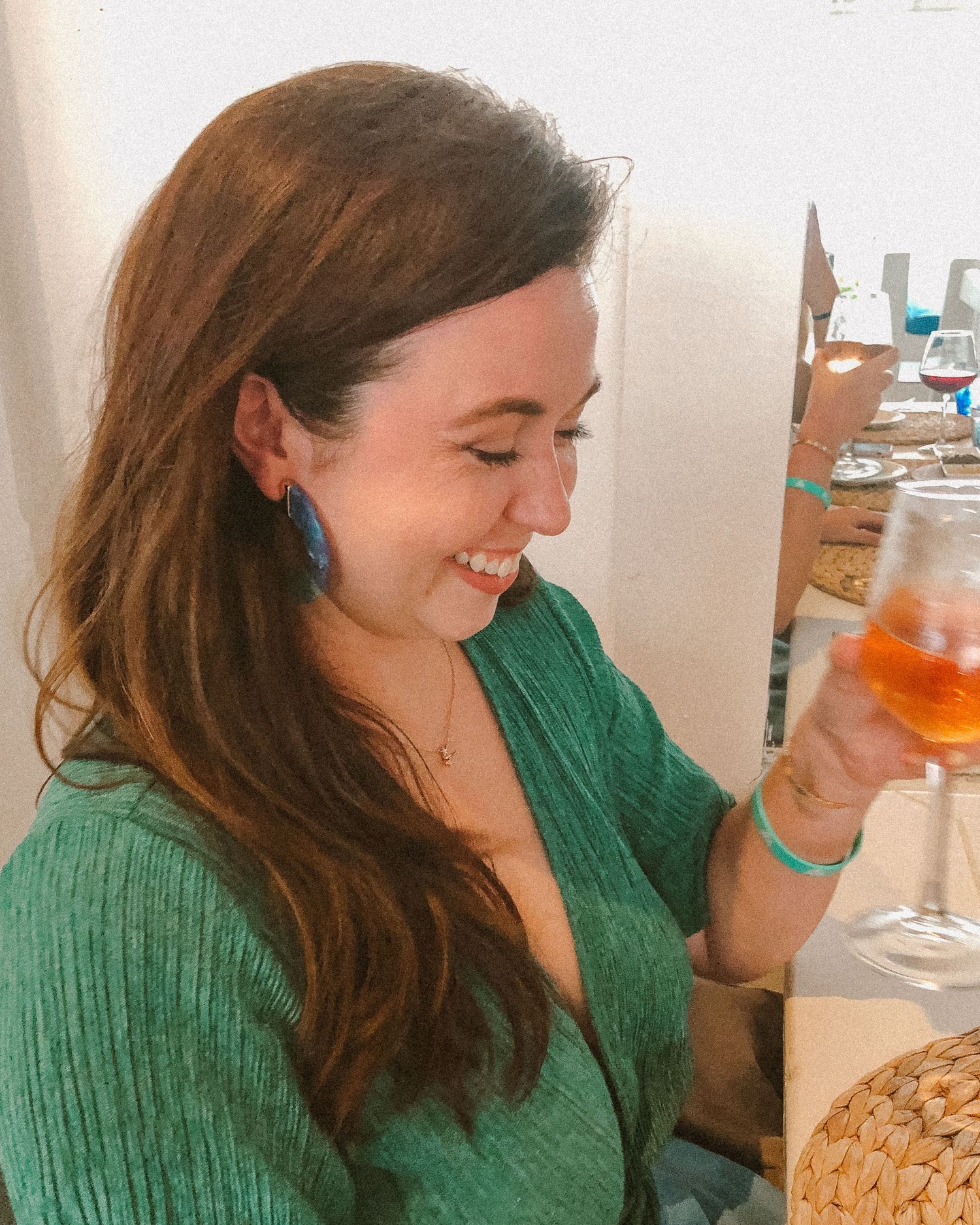 Kelsey, in emerald green dress, smiling while holding wine at dinner in the Bahamas.