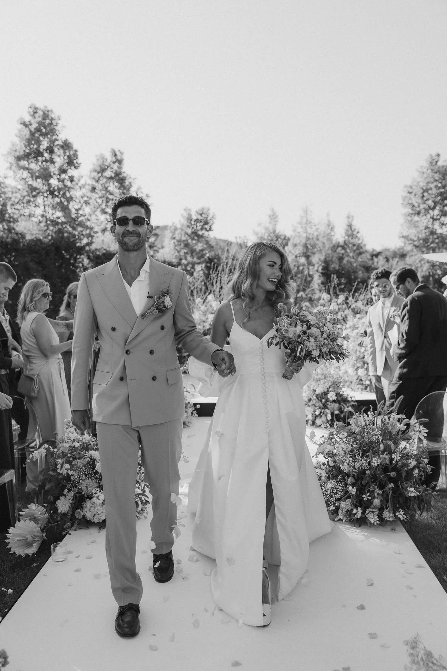 A sequence of black and white wedding photos showing the newlyweds walking and celebrating outdoors.