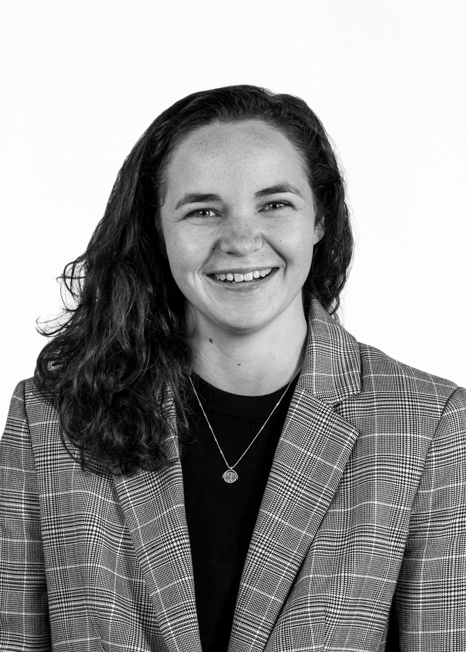 Young woman professional head shot. Black and white. Woman smiling for the camera wearing a pinstripe jacket