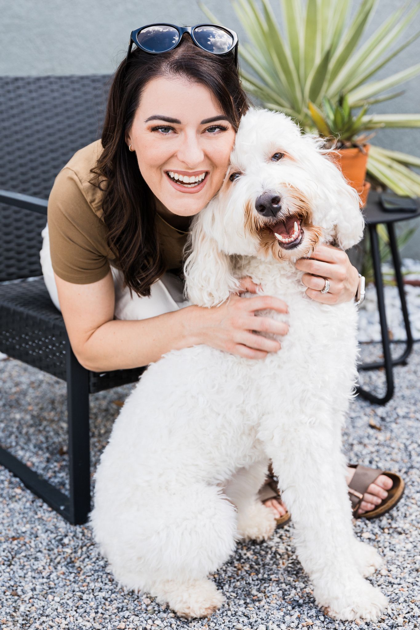 Playful outdoor photoshoot with fluffy white dog on patio furniture.