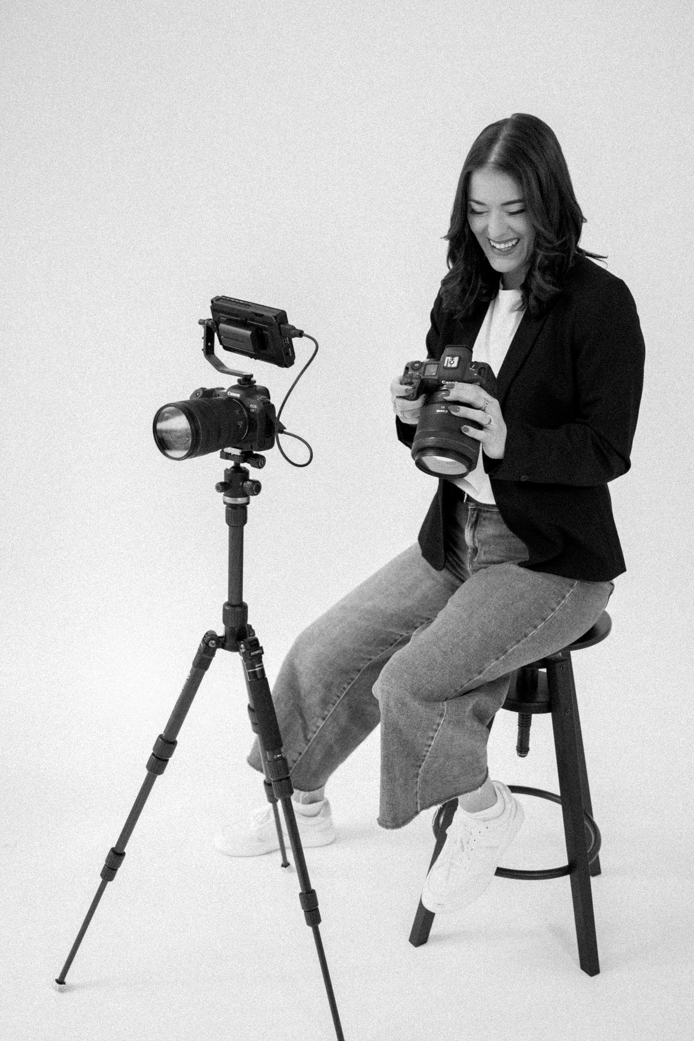 Black and white photography setup with camera on tripod and person adjusting equipment.