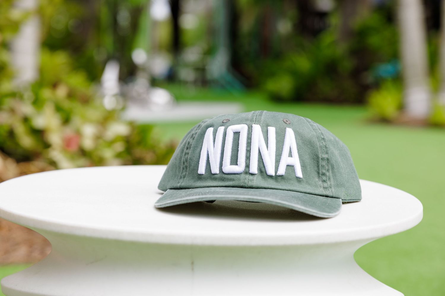 Green baseball cap with text displayed on outdoor surface.