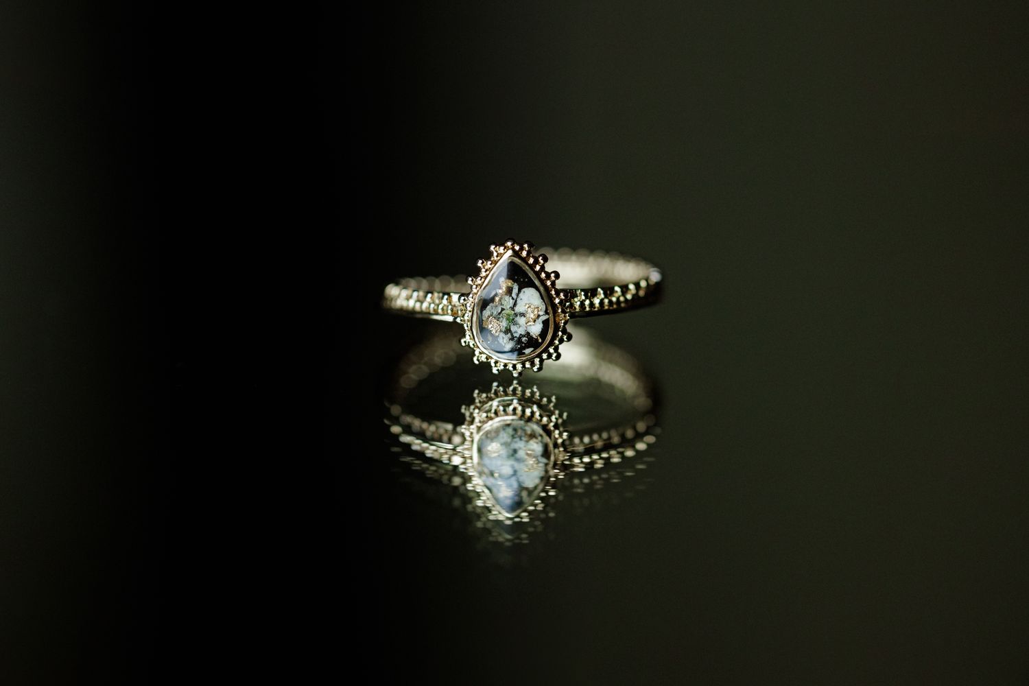 Sparkling diamond ring photographed on dark background with dramatic lighting.