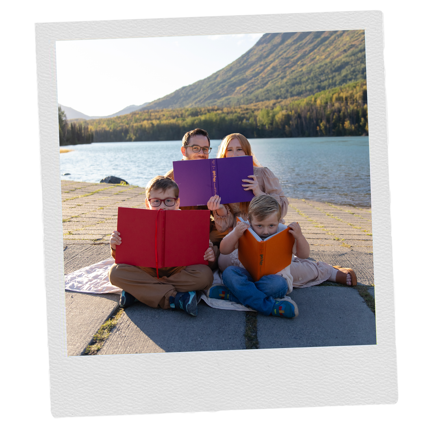 Family members reading books together by a scenic lake in Cooper Landing, Alaska.