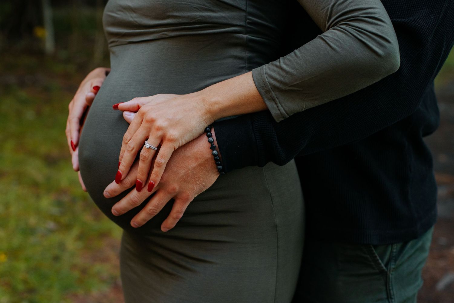 Close-up view of hands resting on gray fabric in natural outdoor setting.