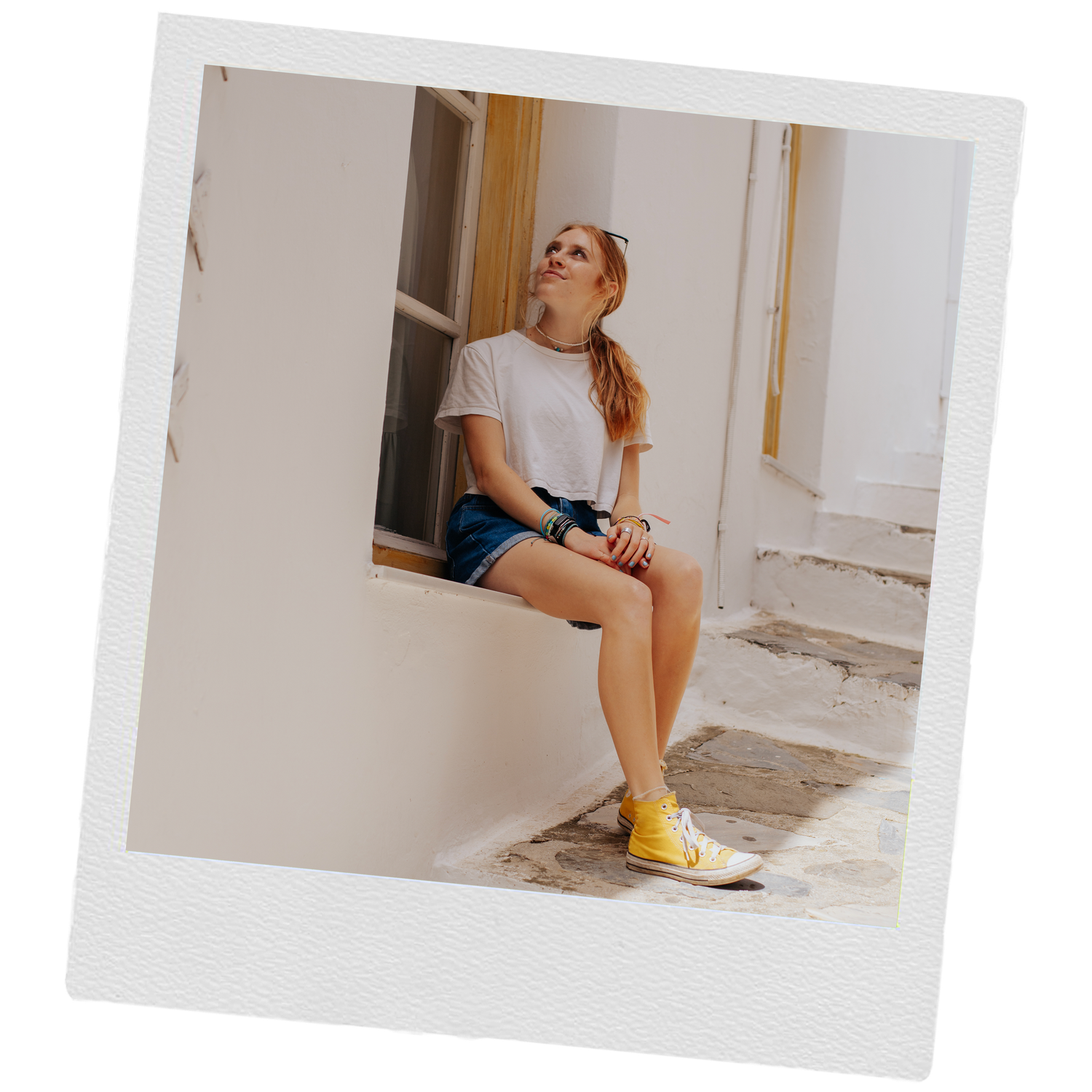 Photographer sitting on white windowsill wearing casual attire and yellow shoes.