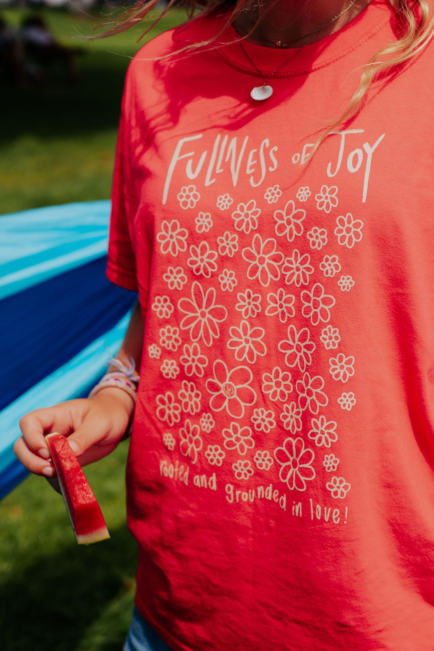 Close-up details of coral colored t-shirt with white floral design pattern.