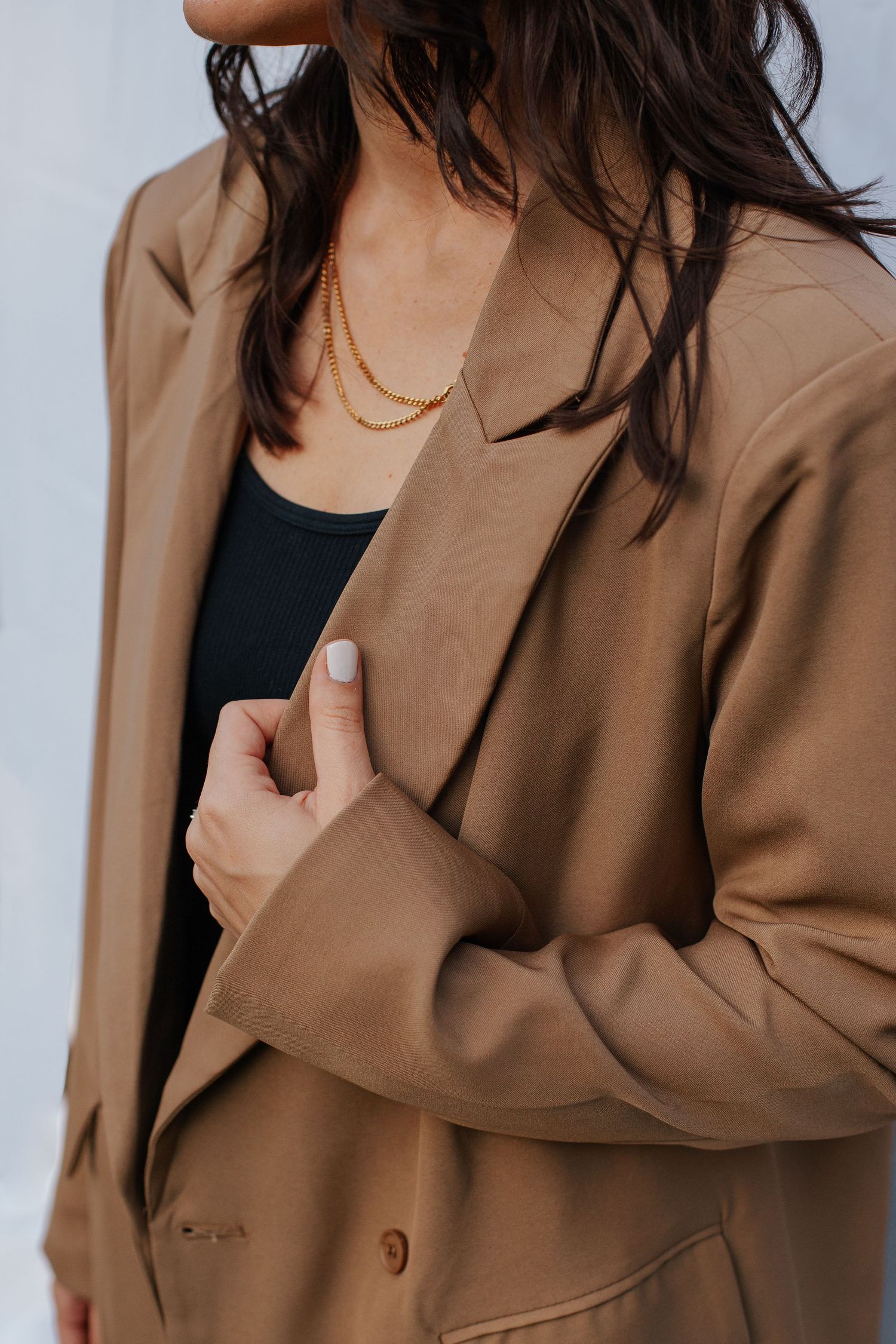 Close-up of tan blazer with black undershirt in studio setting.