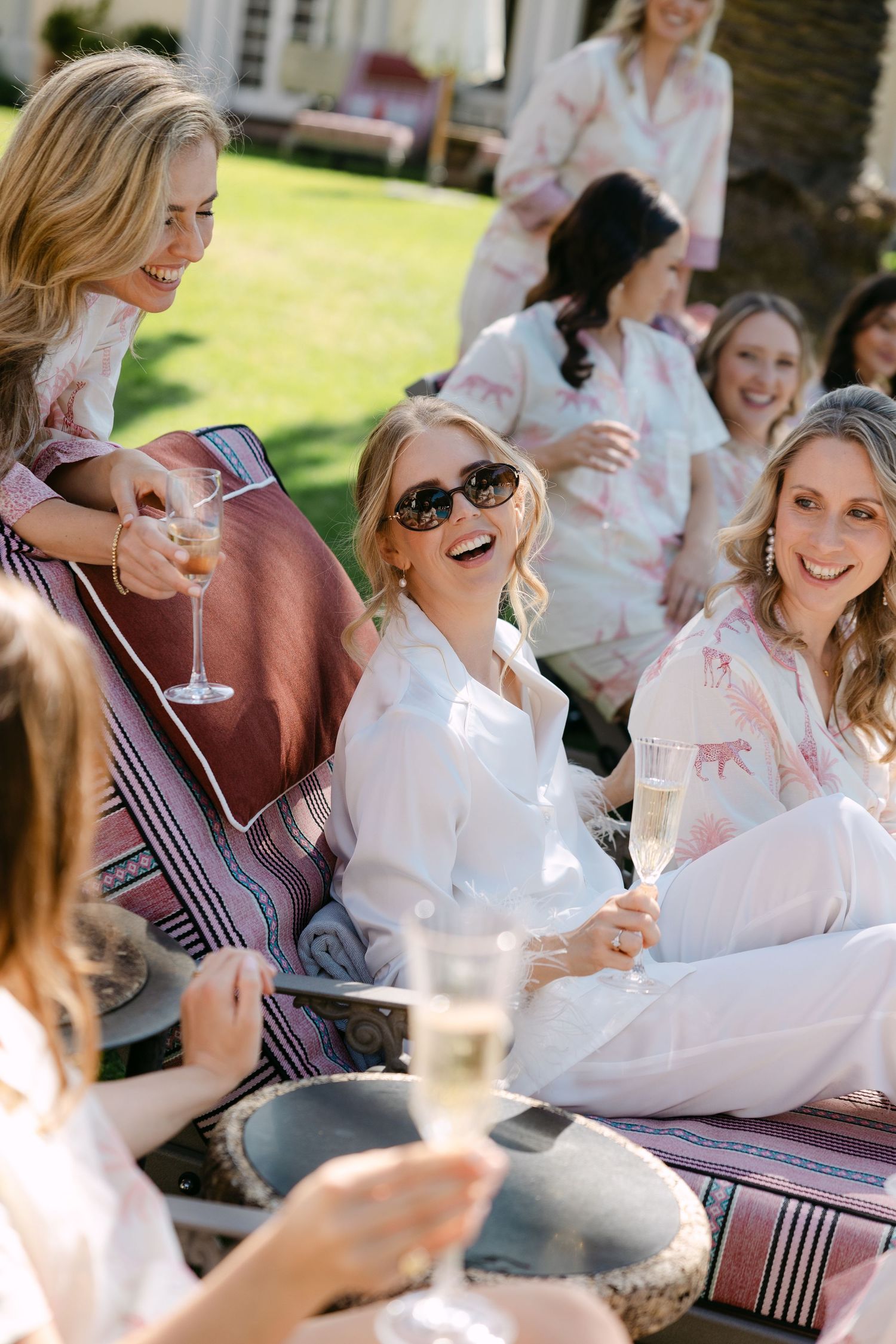 A group of friends enjoying wine and conversation at an outdoor gathering on a sunny day.