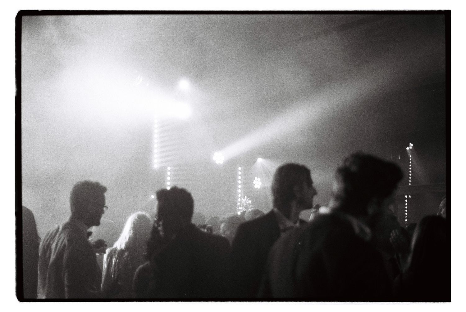 Silhouetted crowd at a wedding reception with dramatic lighting and fog effects.