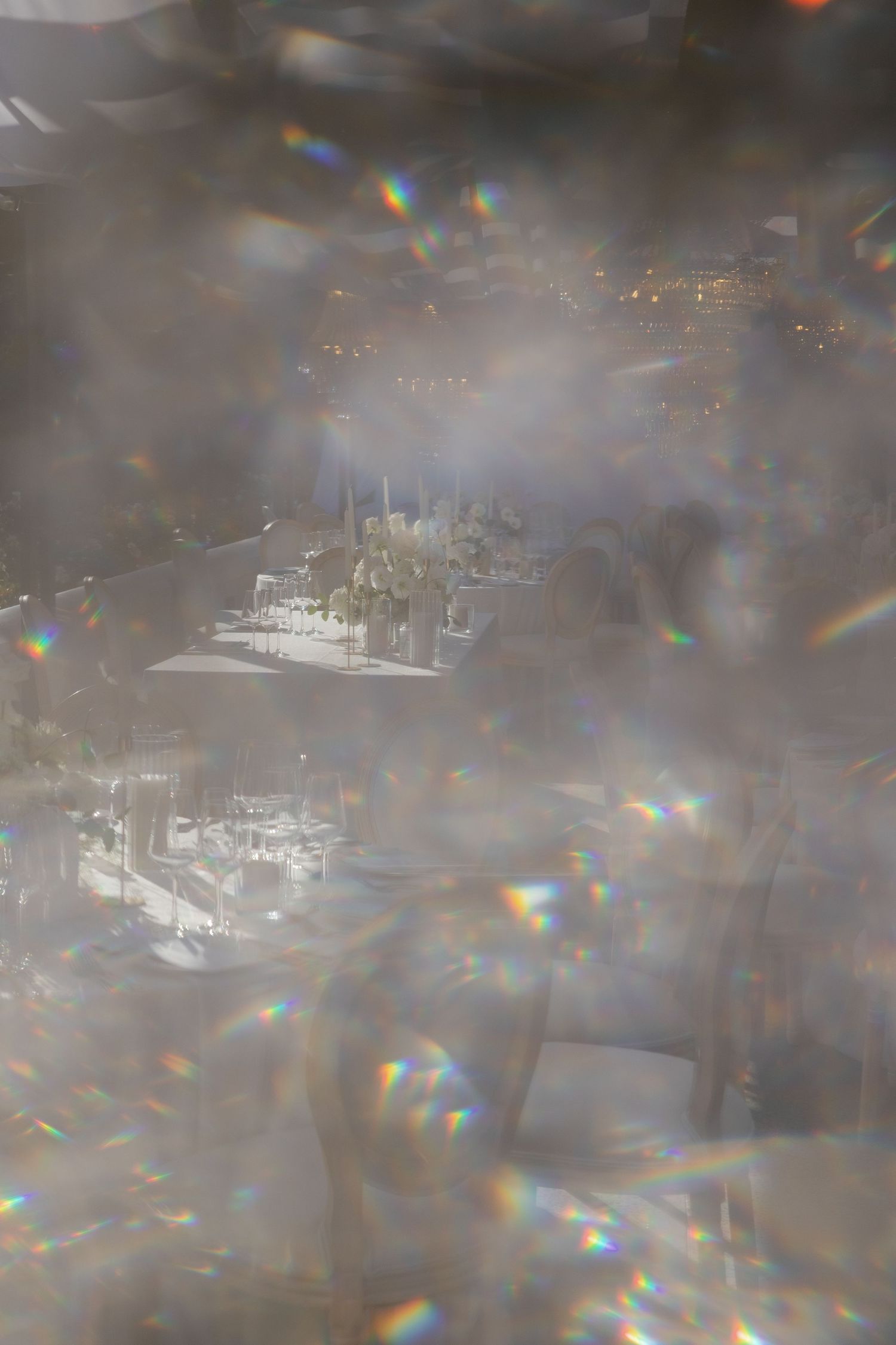 Abstract blurred cityscape view through window glass with rainbow light reflections and bokeh effects.