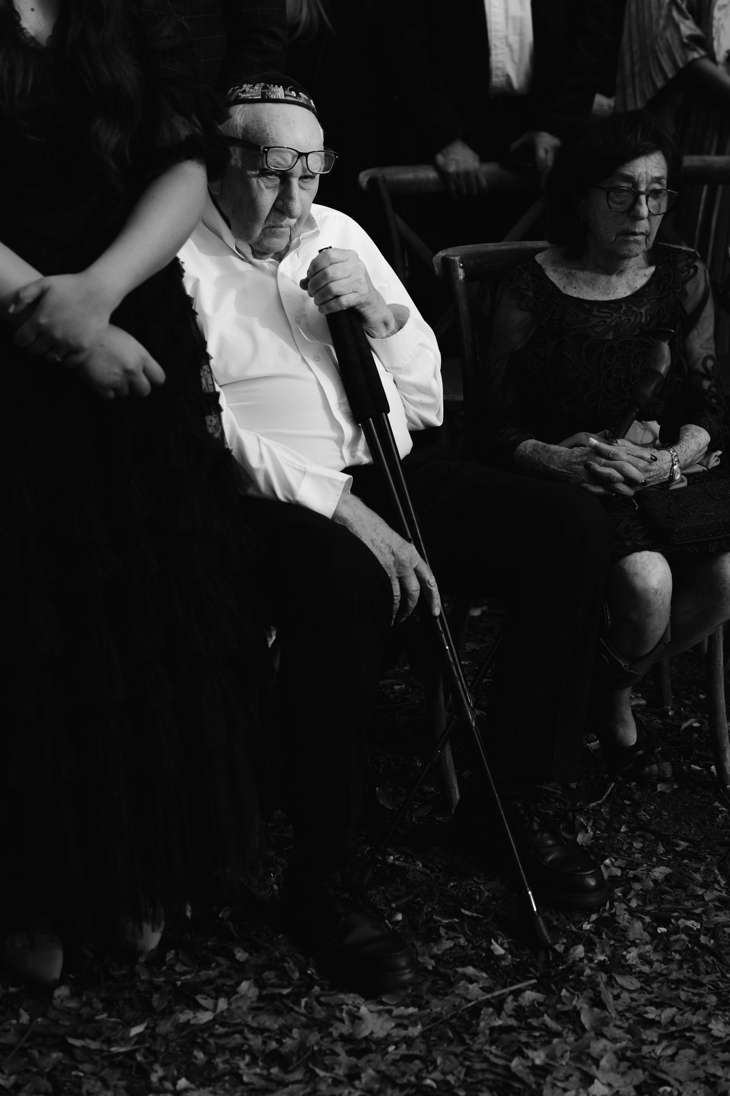 Black and white image of people sitting in a dimly lit setting with dramatic lighting.