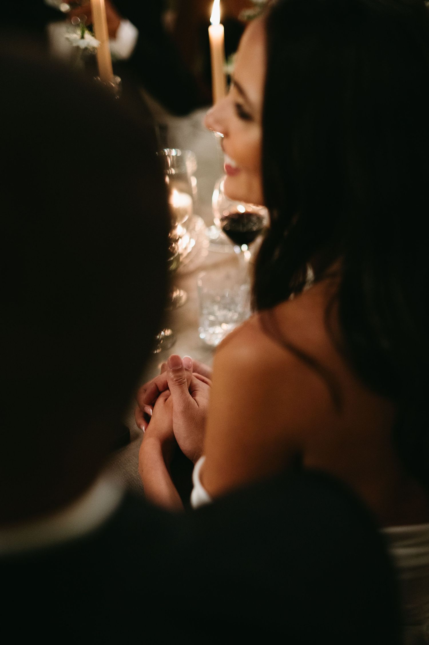 Candlelit wedding reception scene with silhouettes of guests in dark lighting.